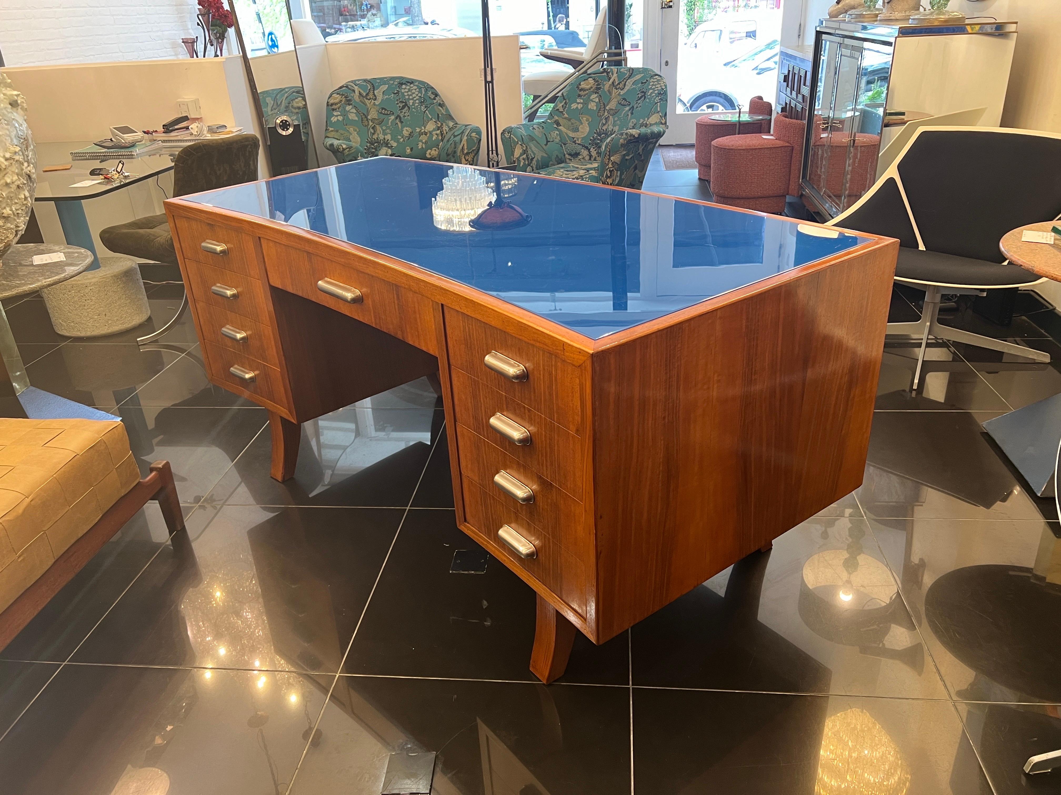An extraordinary C1940 Italian curved desk made from solid cherrywood with a cobalt blue glass top . there’s a total of 9 drawers with their original aluminium handles to the front and a fabulous reeded curved cherrywood to the rear. 
This is a