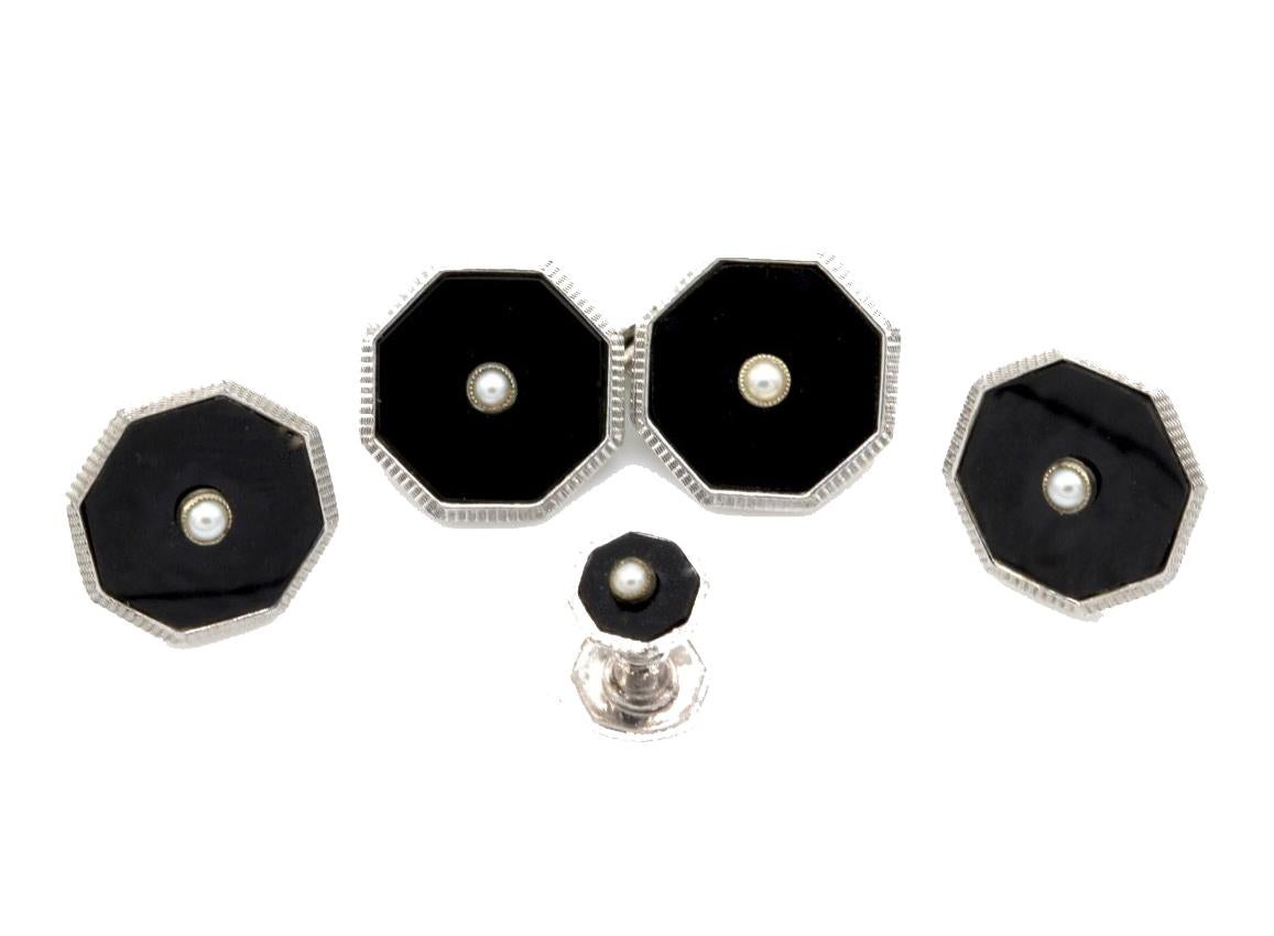 An Art Deco 9 Kt white gold onyx and pearl Gentleman's cufflink and button tuxedo dress set, comprising a pair of cufflinks, four buttons and two collar studs. The 12 mm octagonal links faced in black onyx and edged in white gold with a central