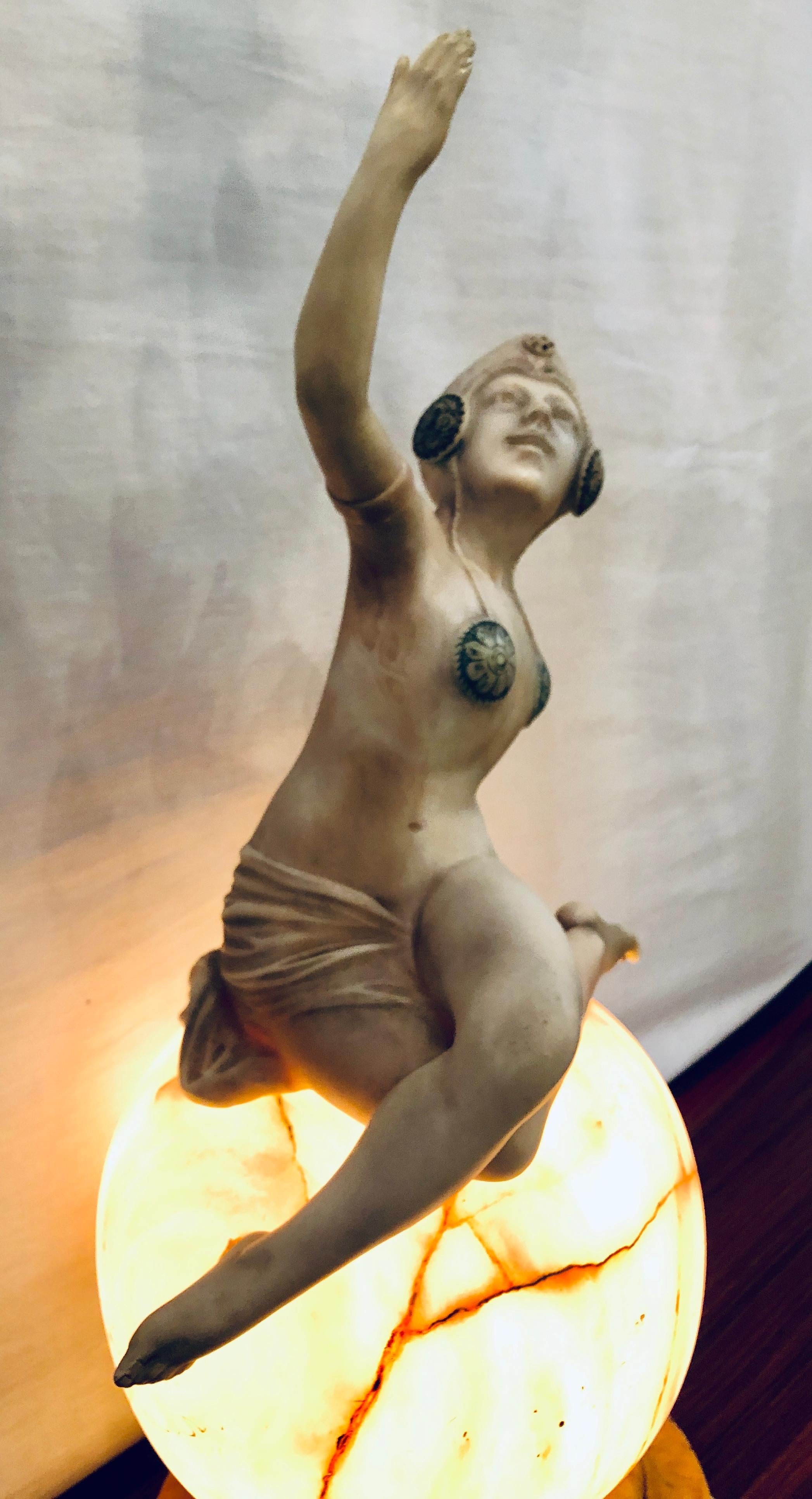 An Art Deco alabaster lamp depicting a dancing can-can girl on top of the world. This lamp is UL listed to take one light bulb. The globe having been repaired however, it may also be the intended design.