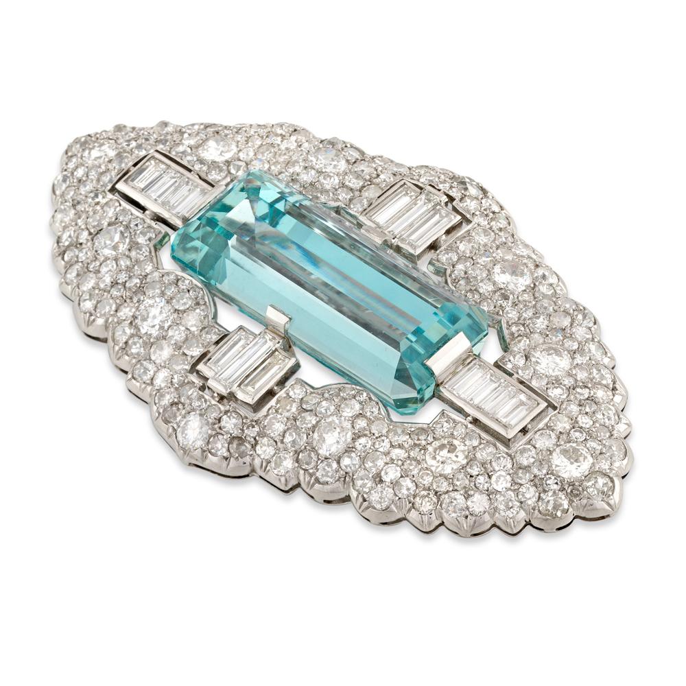 An Art Deco aquamarine and diamond brooch, the emerald-cut aquamarine weighing 27 carats between four sections set with baguette-cut diamonds, all surrounded by a Mughal-style design frame, set with old European and swiss-cut diamonds, the diamonds