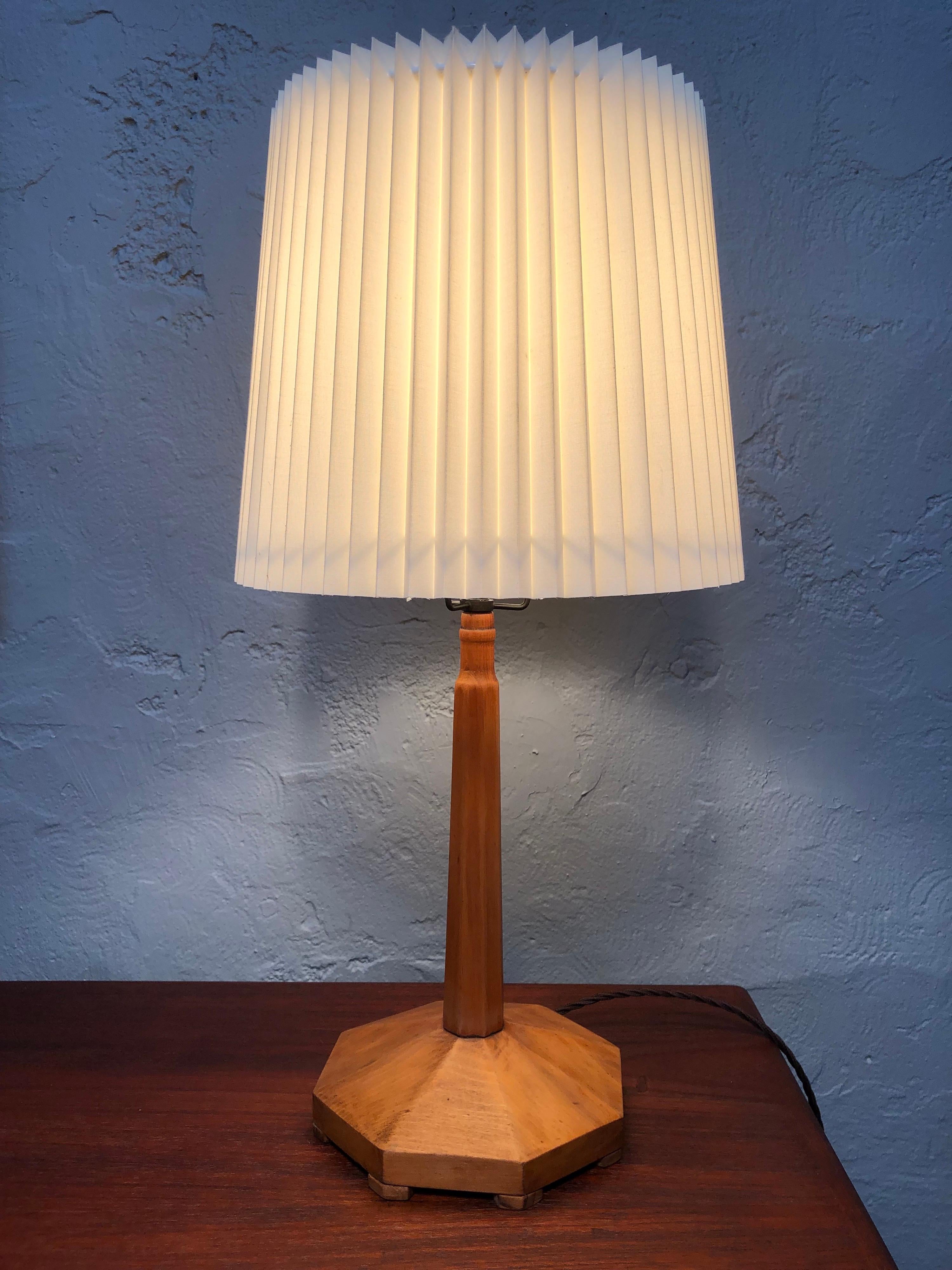 An Art Deco artisan handmade carved table lamp in beech wood. 
Very skillfully executed with a carved octagon shaped base. 
A turned/planed pencil shaped stem. 
Still maintains its original brass and porcelain lamp holder with on/off switch.