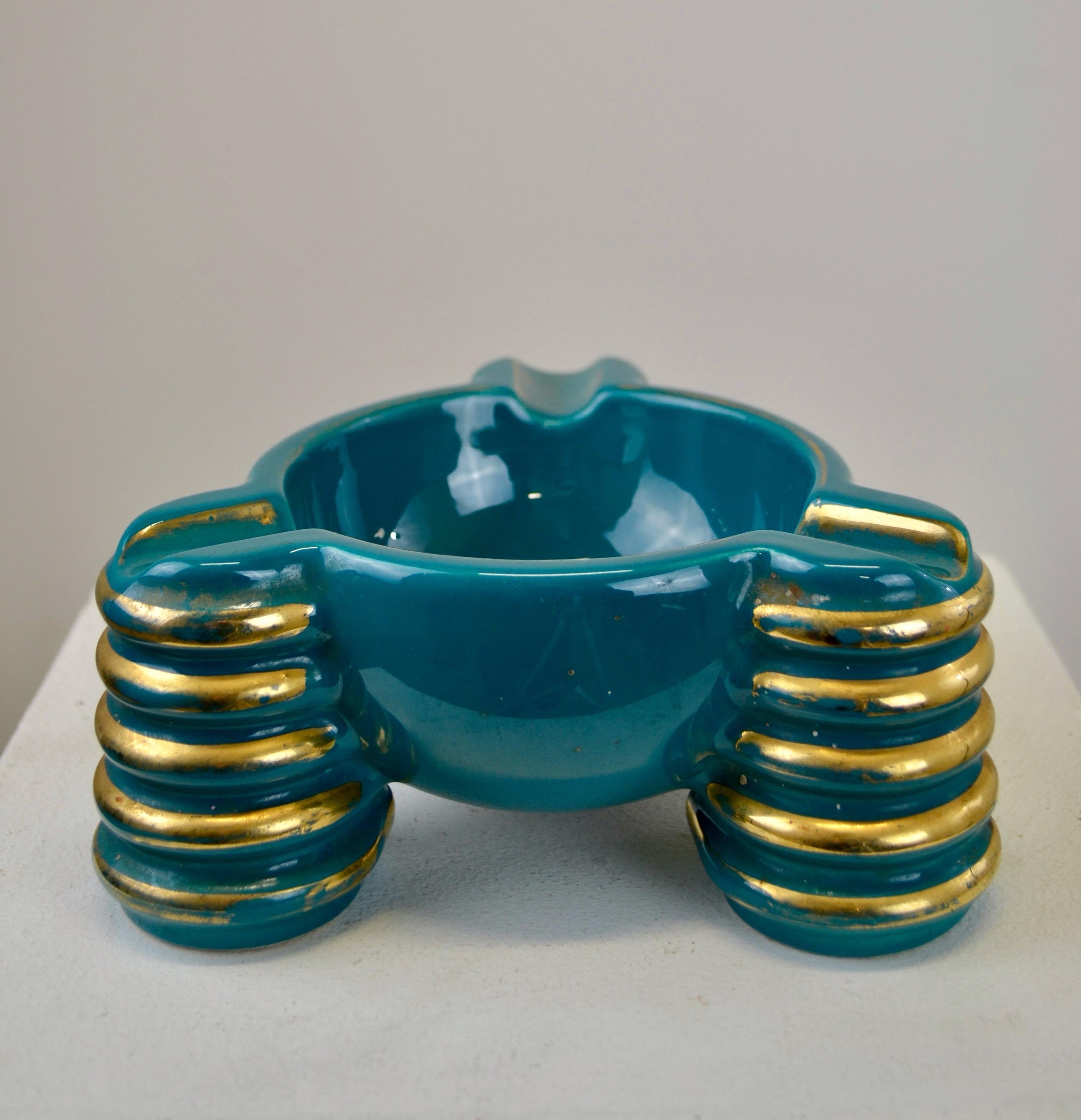 A French Art Deco ashtray in the style of Céramique d'Art de Bordeaux (CAB) or Primavera. This exceptional piece features vibrant blue-green enamel adorned with fine golden details, offering refined elegance. Its futuristic shapes, with golden