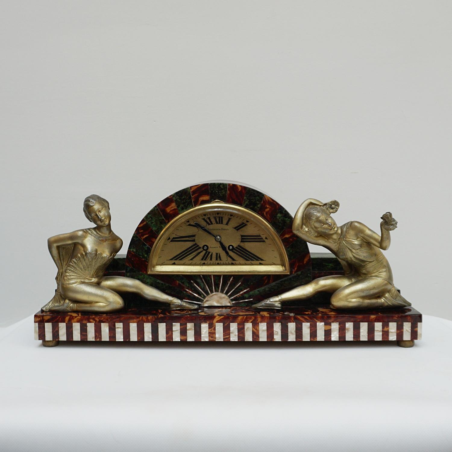 An Art Deco clock with spelter ladies. Brown and green marbled bakelite surround. Spelter clock face with roman numerals.

Dimensions: H 33.5cm W 54.5cm D 16.5cm 

Origin: English 

Date: circa 1930

Item Number: 0306231.

.