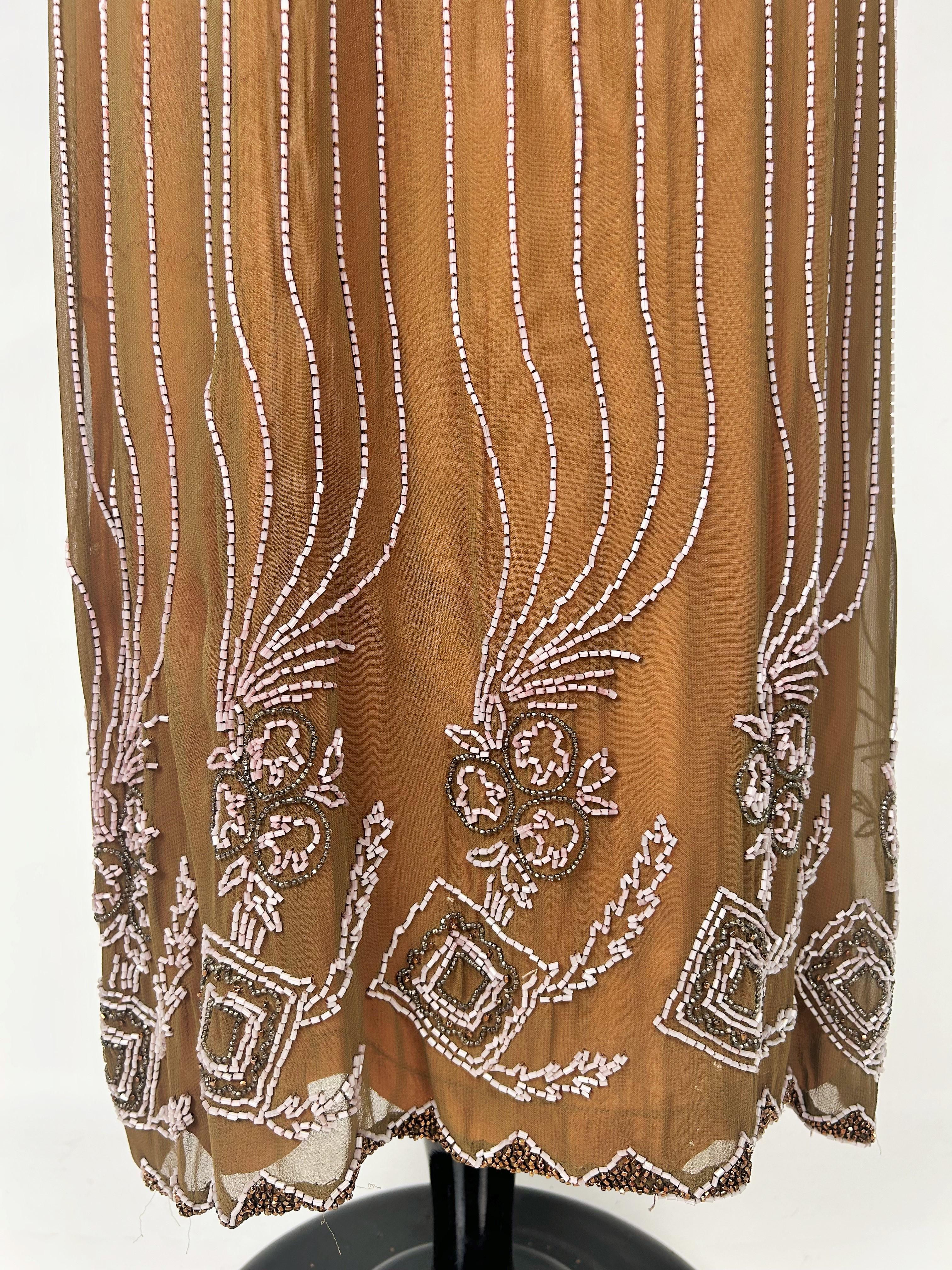 Vers 1920-1925
France
Elegante robe du soir en mousseline de crêpe de soie couleur chamois brodée de perles, datant du début de la période Art Déco en France. Coupe sac ample et droite, encolure bateau et manches kimono, entièrement brodée de perles
