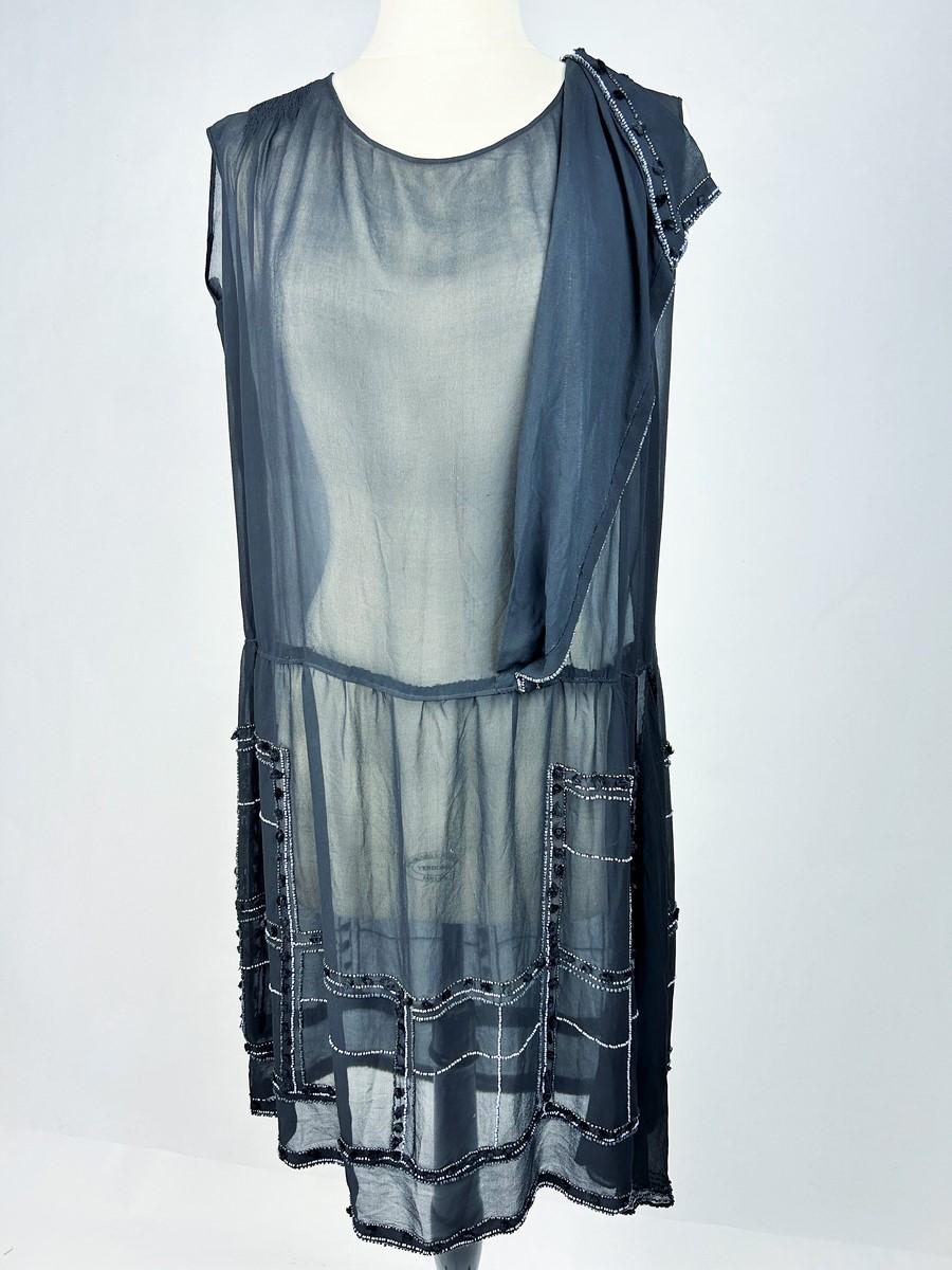 Alrededor de 1925-1930 Francia. Vestido corto de gasa de seda negra bordada con cuentas de cristal lila y perlas de marcasita del periodo Art Déco.  ¡Aquí, el tema del vestidito negro celebrado por Gabrielle Chanel y sinónimo de Chic à la française!