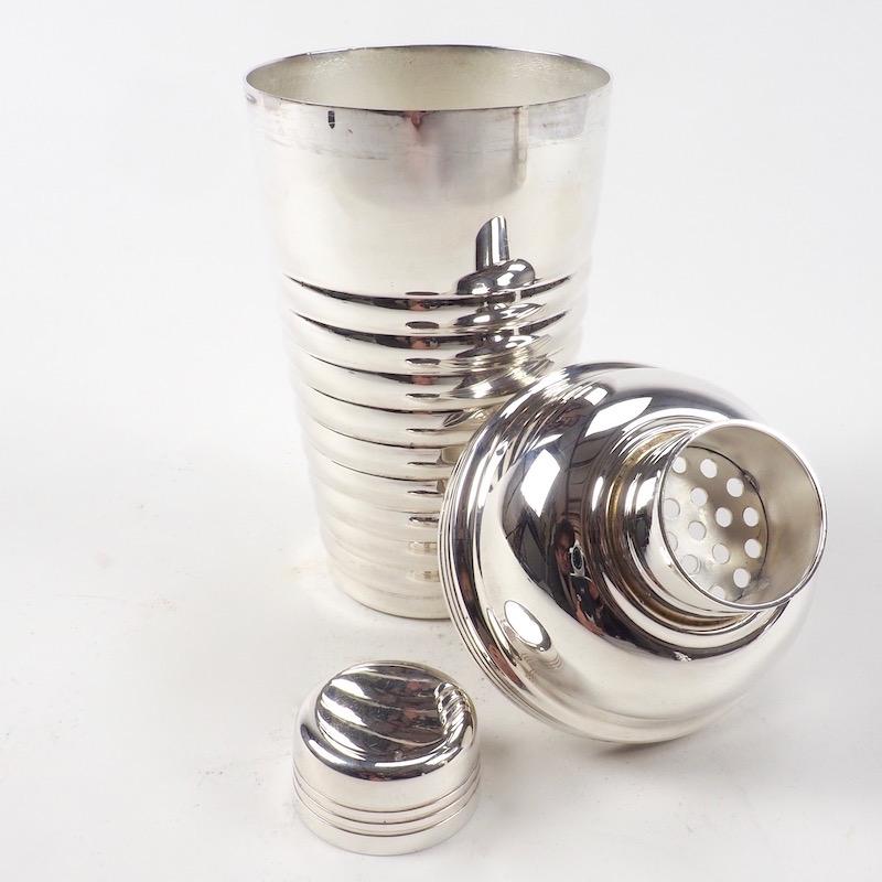 An Art Deco cocktail shaker of stylish curves and lobed horizontal ribs. The fluid lines and bold modernist design are indicative of the chic elegance of the era.