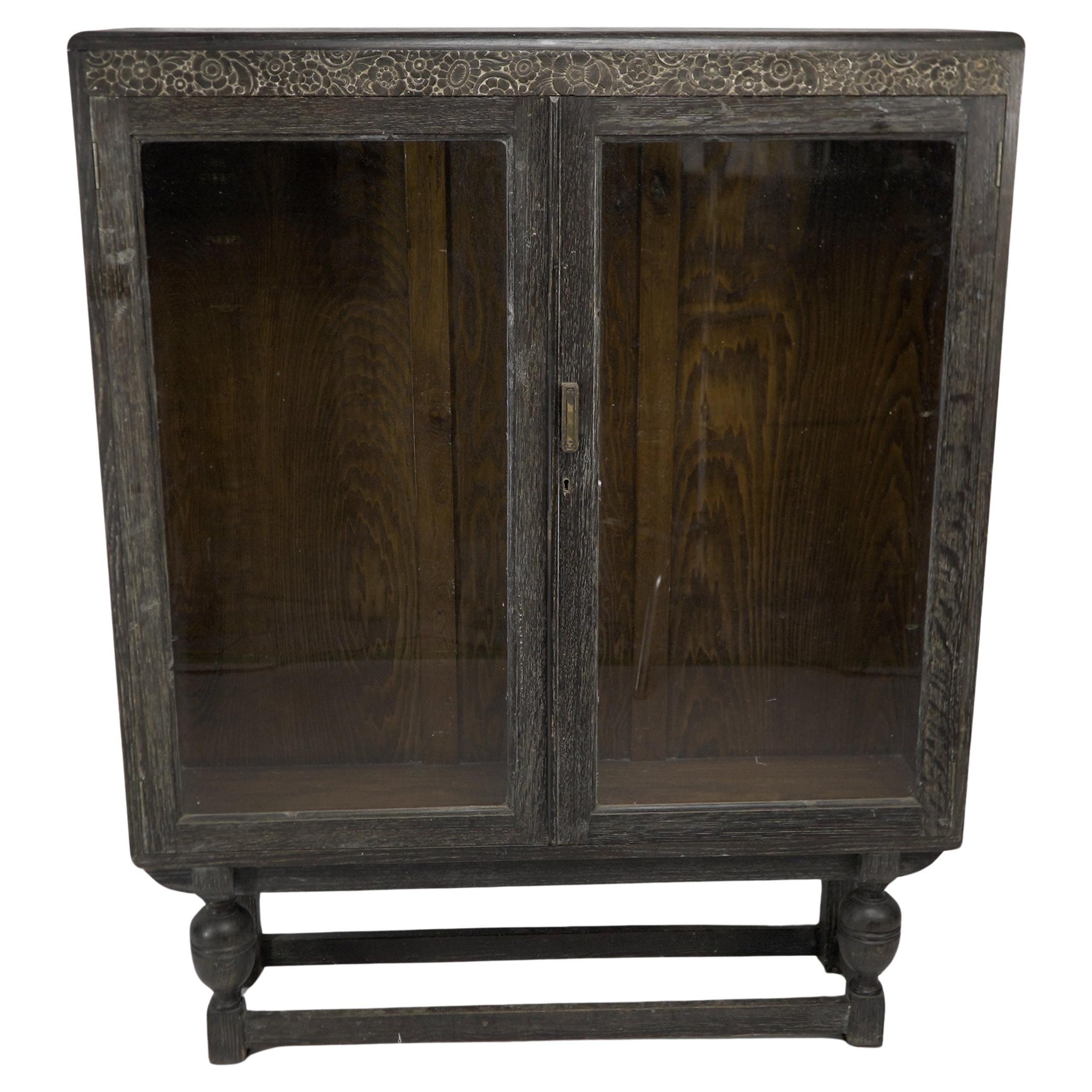 An Art Deco dark and limed oak glazed bookcase with carved floral decoration. For Sale