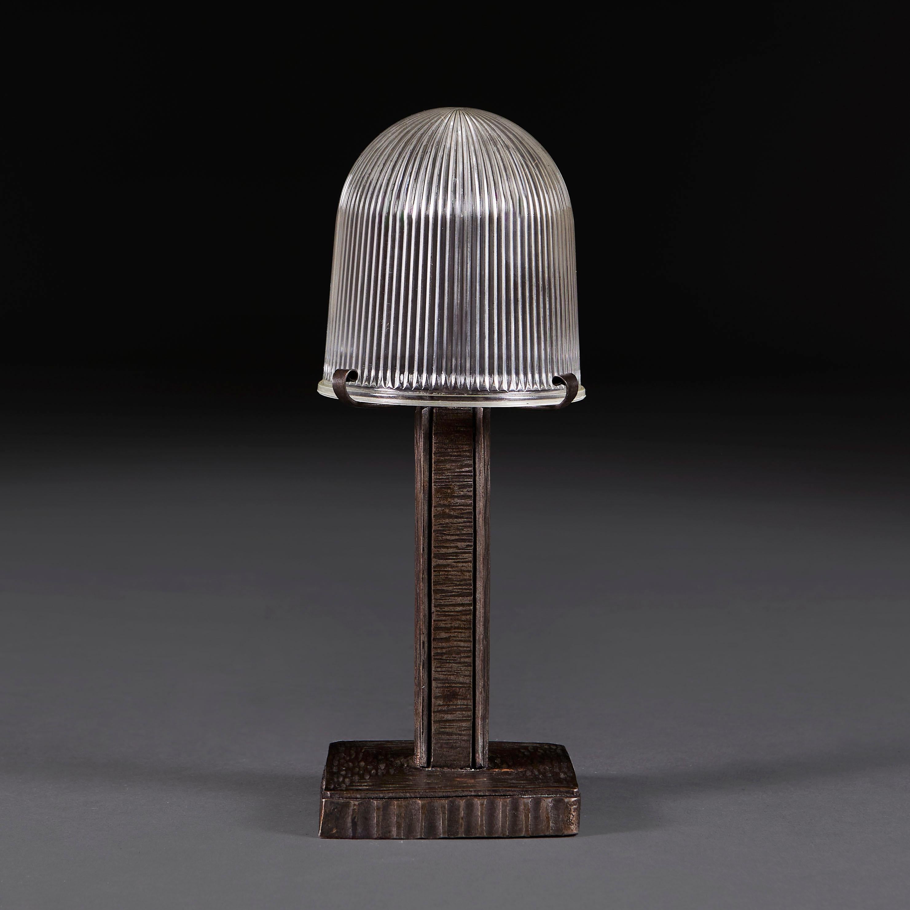 France, circa 1920

A small Art Deco wrought iron desk lamp with square plinth base, the stem decorated with horizontal incised lines, supporting a ribbed domed glass shade.

Height 28.00cm
Width of base 10.00cm

Please note: This is currently wired