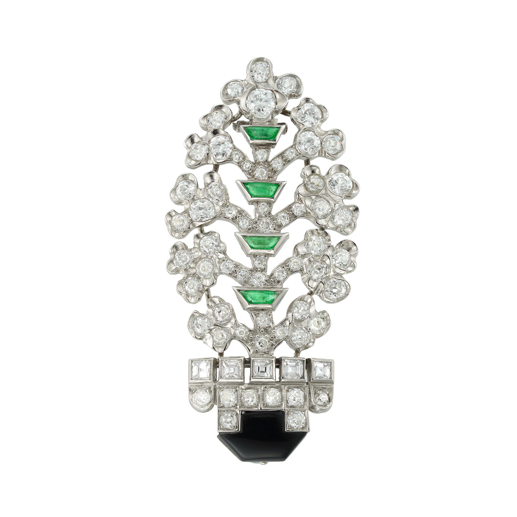 An Art Deco diamond, onyx and emerald giardinetto brooch, the pot formed by an onyx embellished with eight old-cut diamonds, the rim flanked with five carre-cut diamonds, the trunk of the tree formed by four trapeze shaped cabochon-cut emeralds and