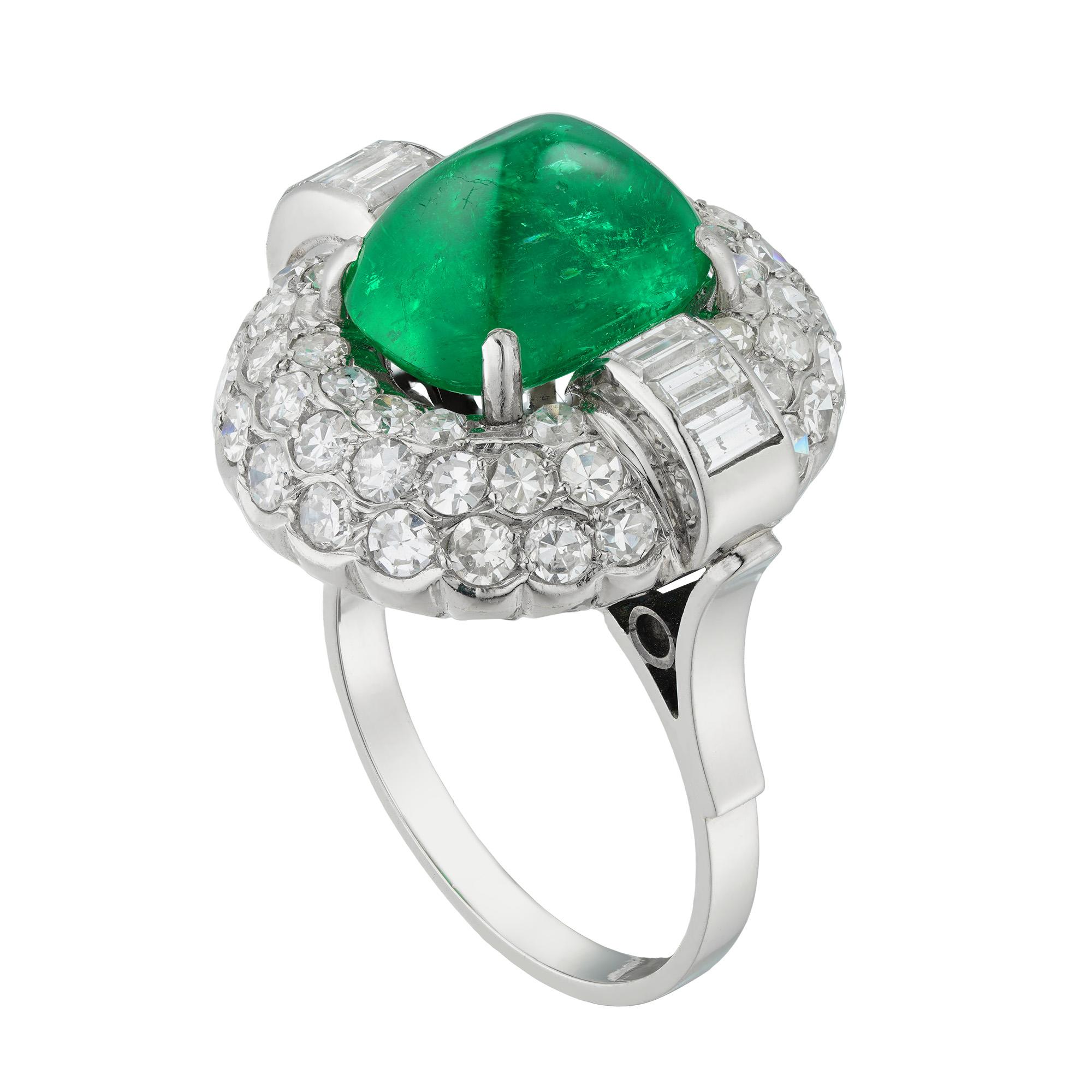 An Art Deco Colombian emerald and diamond bombe cluster ring, the oval shaped sugarloaf-cut emerald weighing 5.62 carats accompanied by GCS report stating to be of Colombian origin, four claw set between two sections each with three rolling