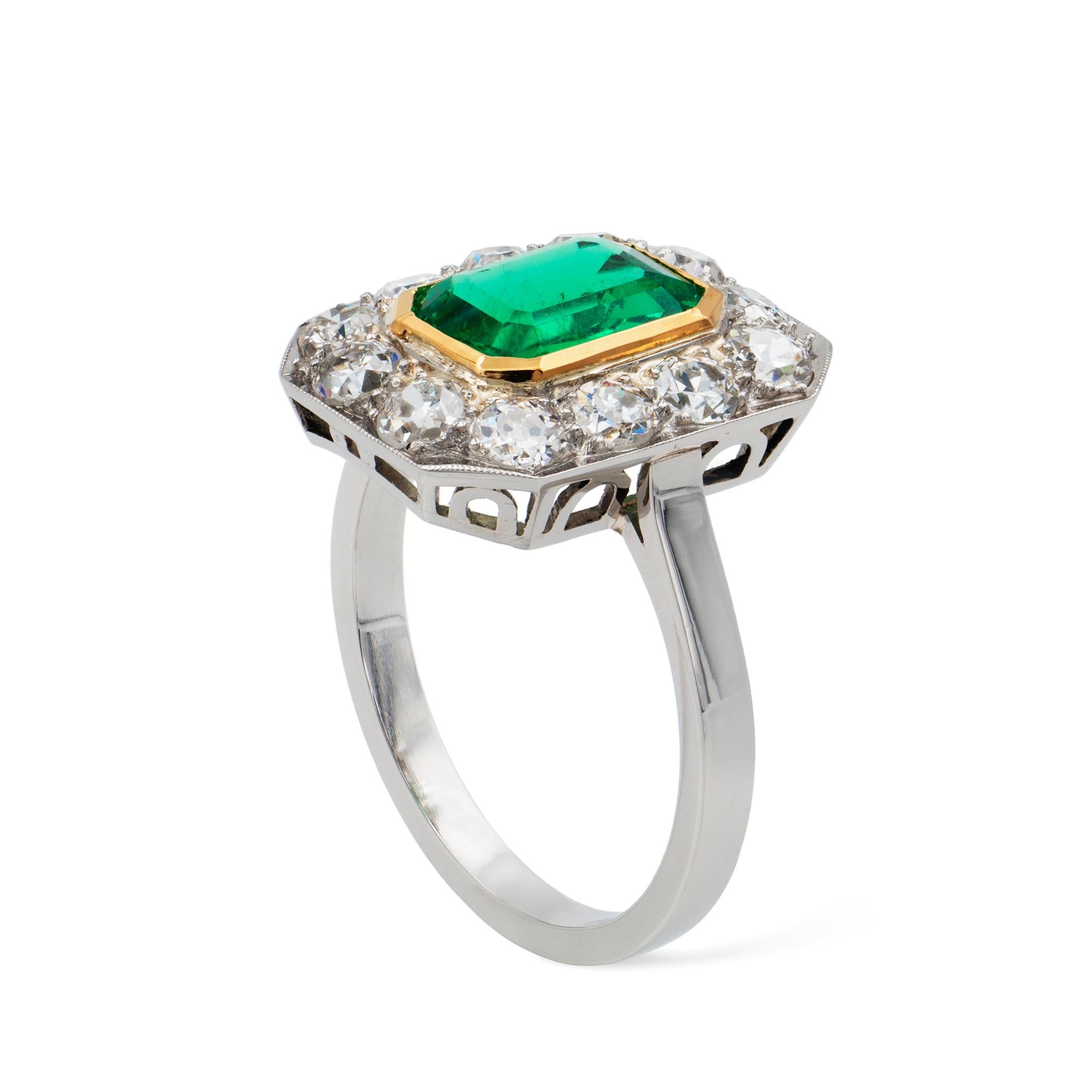 An Art Deco emerald and diamond cluster ring, the 1.22 carats octagonal-cut emerald accompanied by GCS Report, stating to be of Colombian origin with minor clarity enhancement, rub-over set in yellow gold collet, surrounded by an octagonal frame set