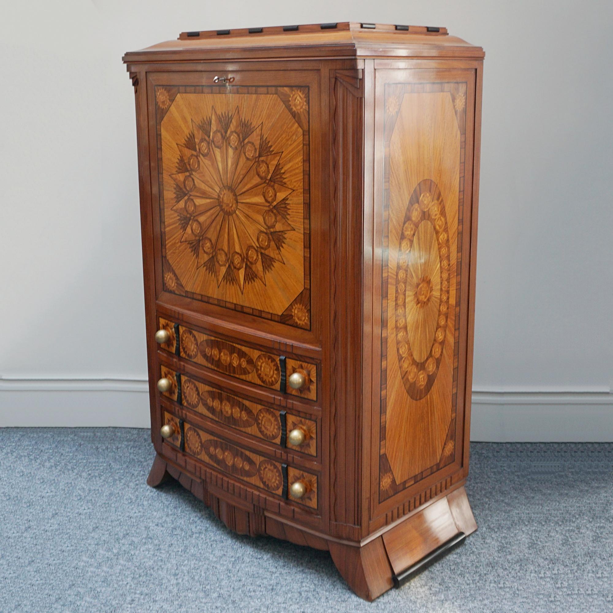Un armadio secretaire con ante a ribalta in stile Art Déco. Impiallacciato in legno di raso ed ebano macassar su rovere massiccio, con intricati dettagli a intarsio sia all'esterno che all'interno. Tre cassetti inferiori ben proporzionati con