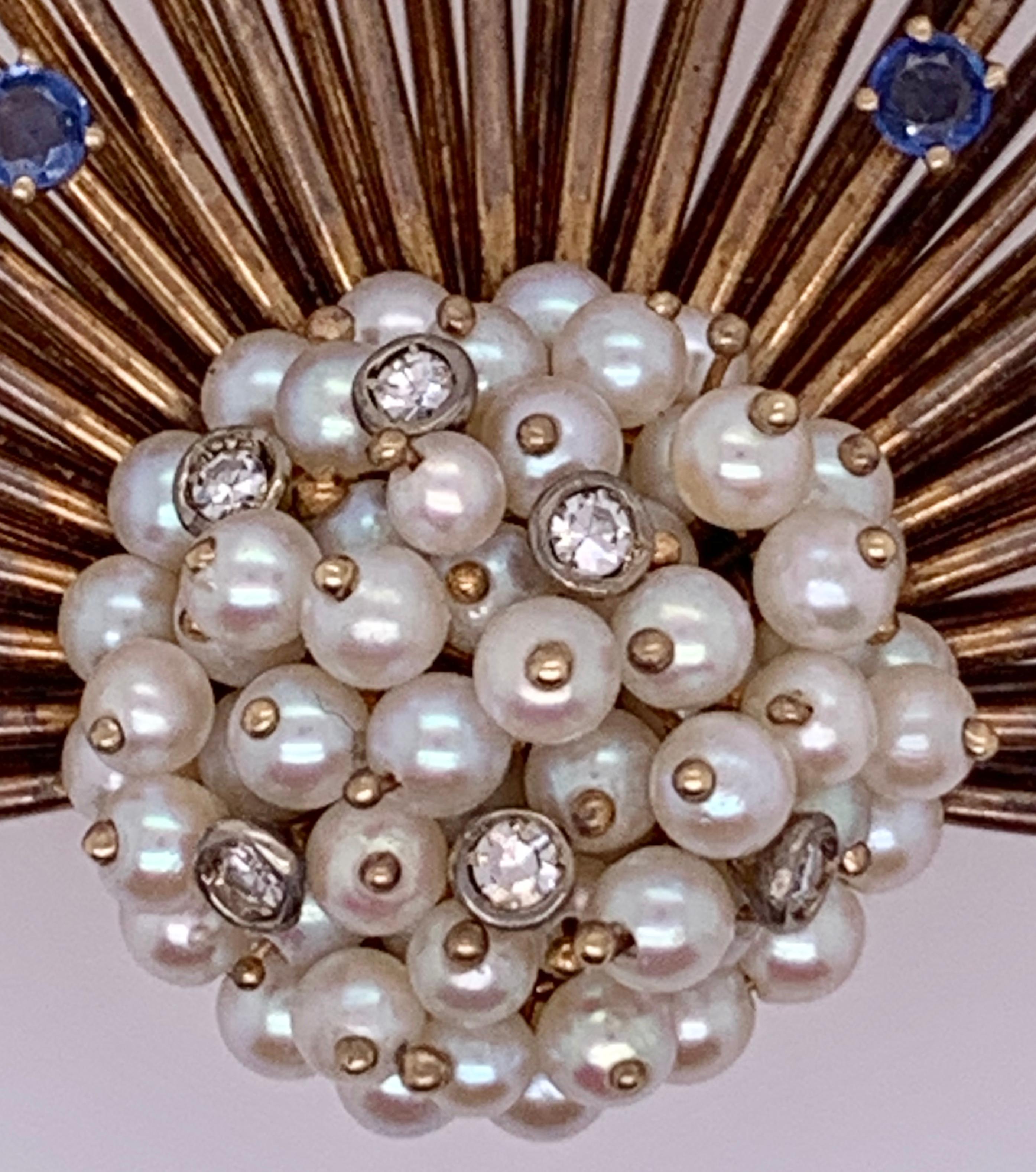 An Art Deco Fan Brooch / Pin. Diamond and Pearl in 14K Yellow Gold. The center cluster of pearls approximately 3.3mm in size with six diamonds leading to five sapphires terminating in 45 pearls the largest of which stands in the center at 4.25mm.