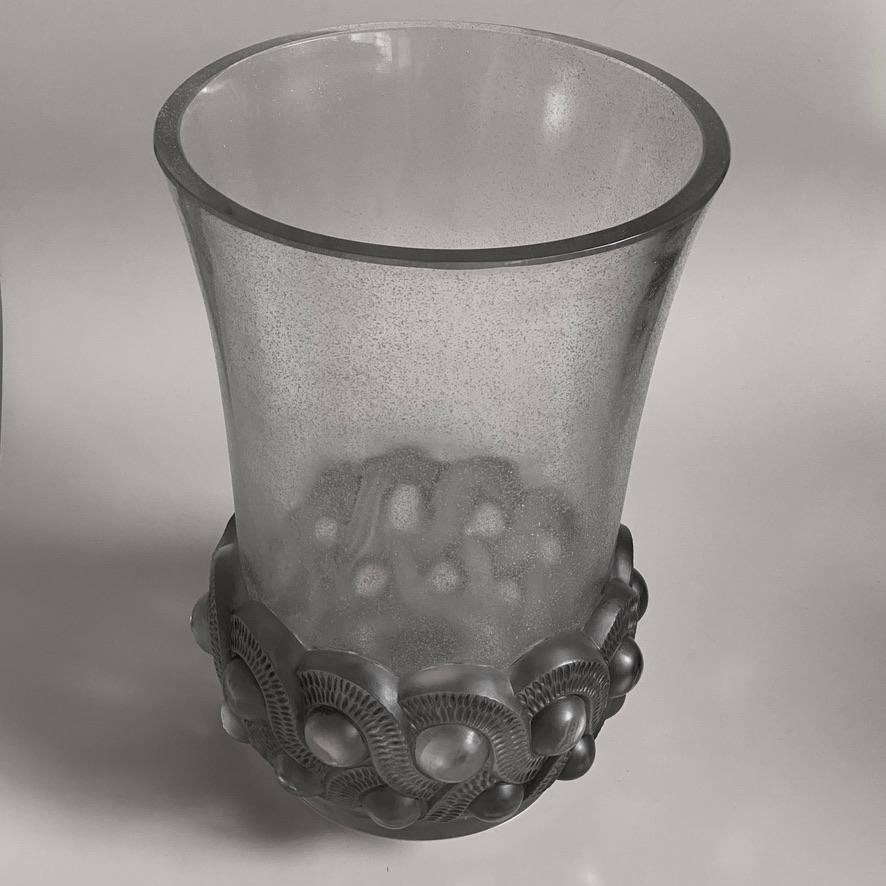The Gao vase is an exceptional Art Deco model designed by R.Lalique.

The bracelet shaped bottom of the vase strongly reminds of the Art Deco jewelers and bracelets of that time .

The long body of the vase is in strong sand blasted