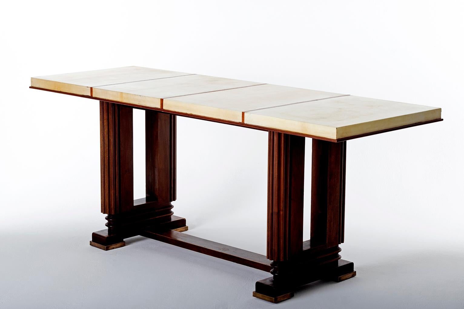 An Art Deco mahogany and velum console table, by Gauthier-Poinsignon, of very generous proportions.
The base with bronze feet, of geometrically stylized lyre shape, supporting a top of for sections covered in velum
France, circa 1925.