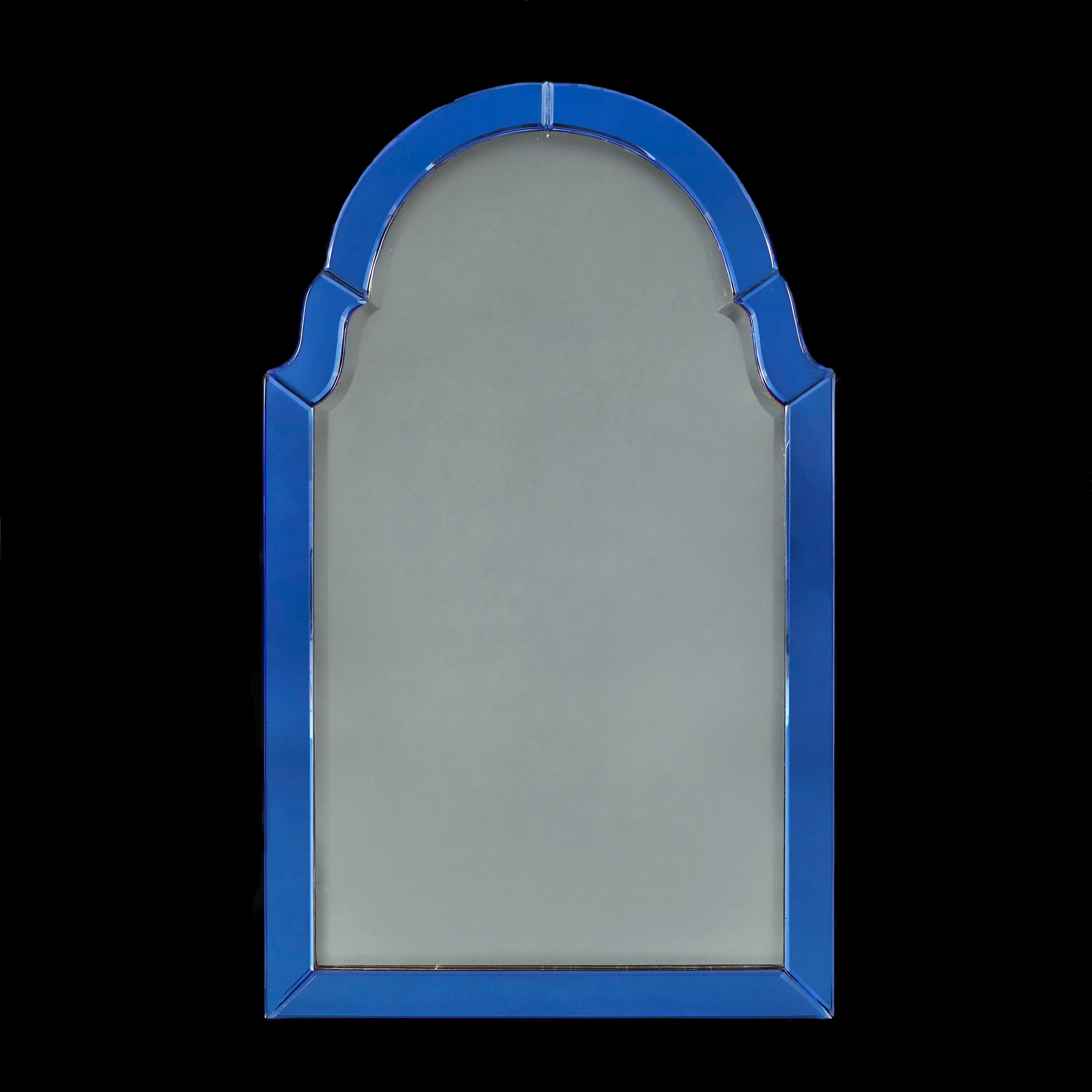 A striking Art Deco mirror with arched pediment, the central shaped and beveled plate framed by blue glass borders with beveled edges.