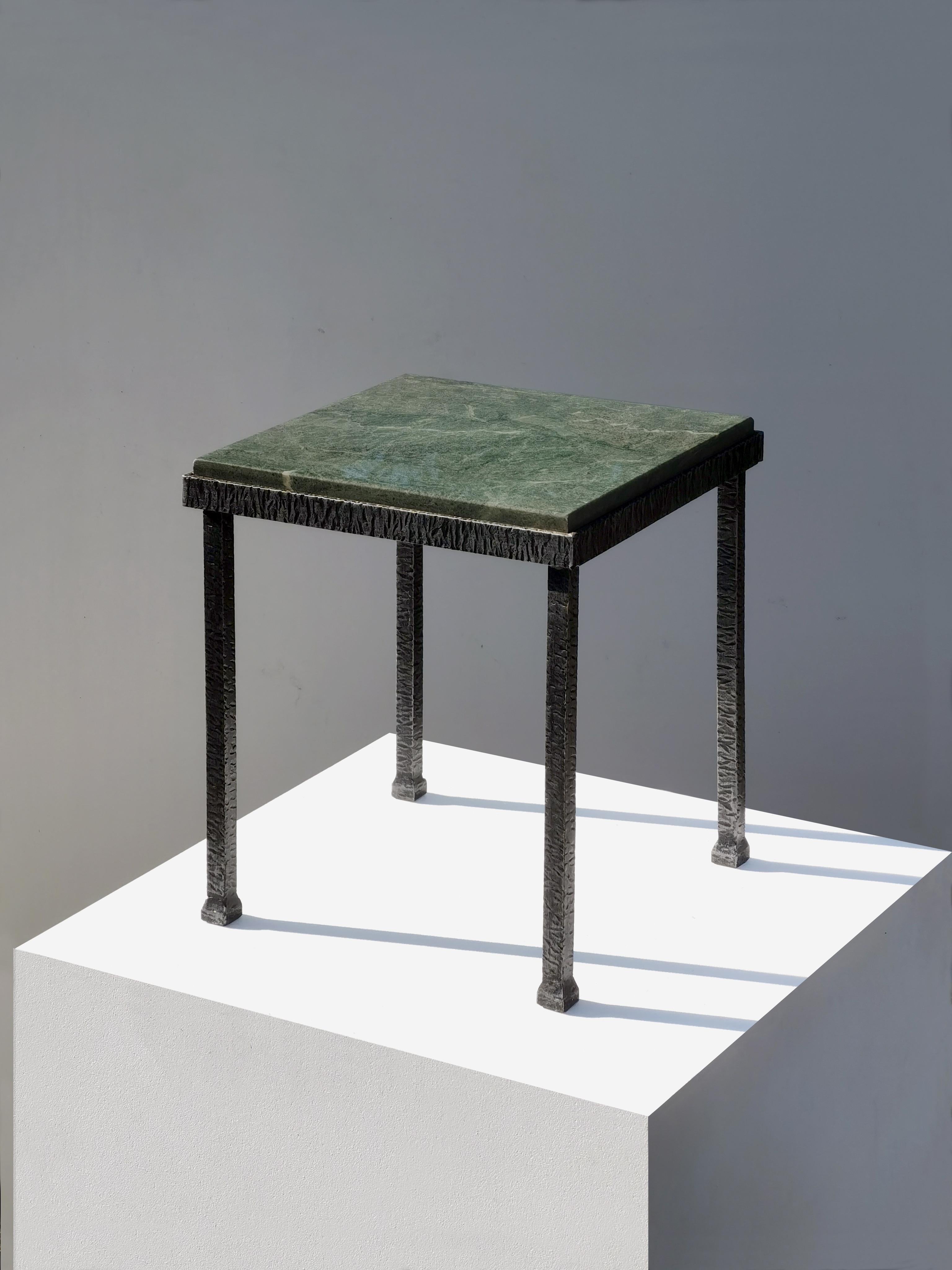 Mesa auxiliar o de noche elegante, rigurosa y escultural, Art Déco, Modernista, Neoclásica, estructura de hierro forjado martillado con tapa cuadrada de mármol verde celadón, según el espíritu de Edgar Brandt, pendiente de atribución, Francia. 