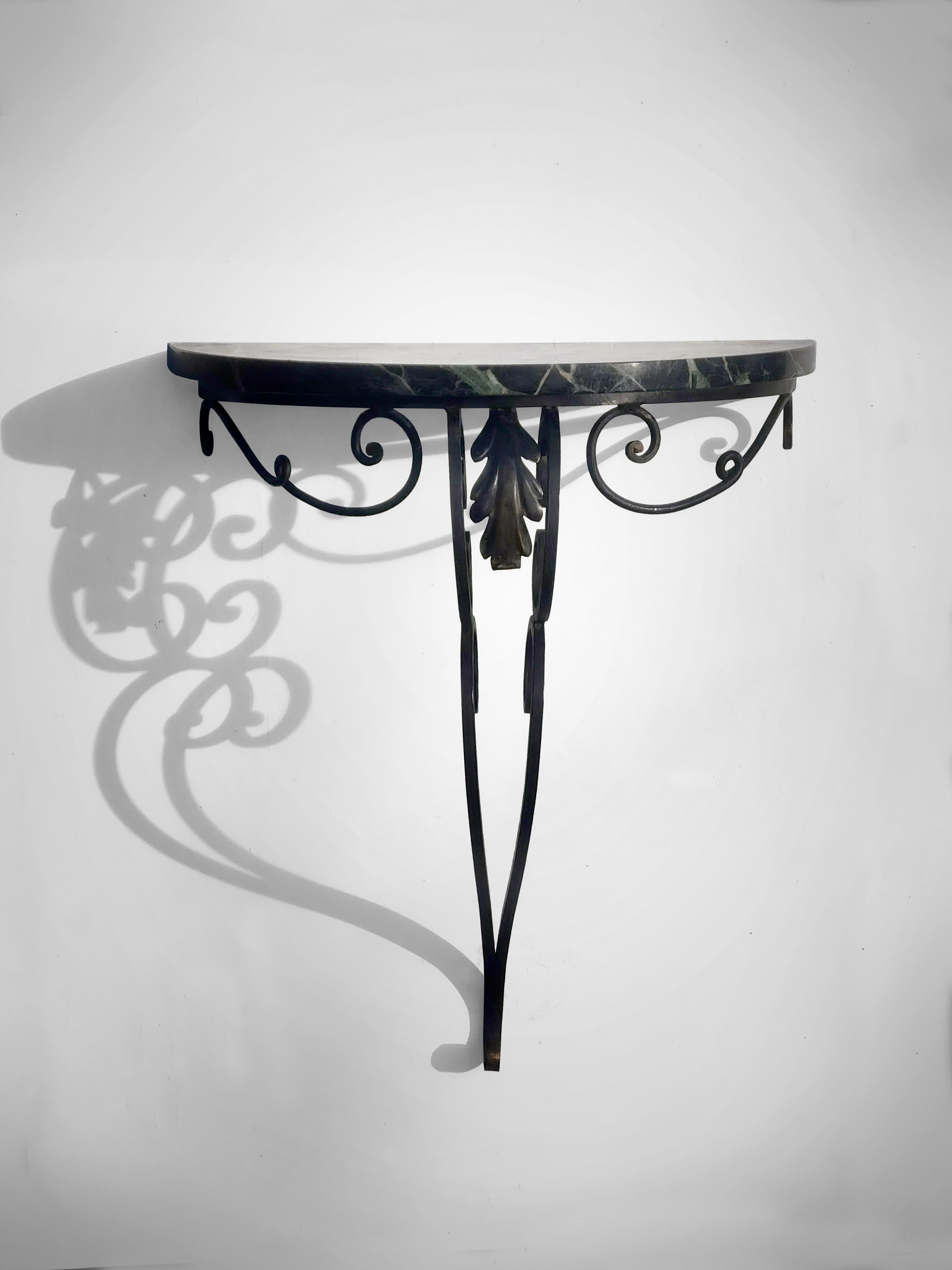 Elegante consola de pared, Art decó, modernista, neoclásica, estructura de hierro forjado de superbanda sensual con pátina dorada en los extremos giratorios, con tapa circular de mármol verde intenso, pendiente de atribución, Francia  1930s. Para