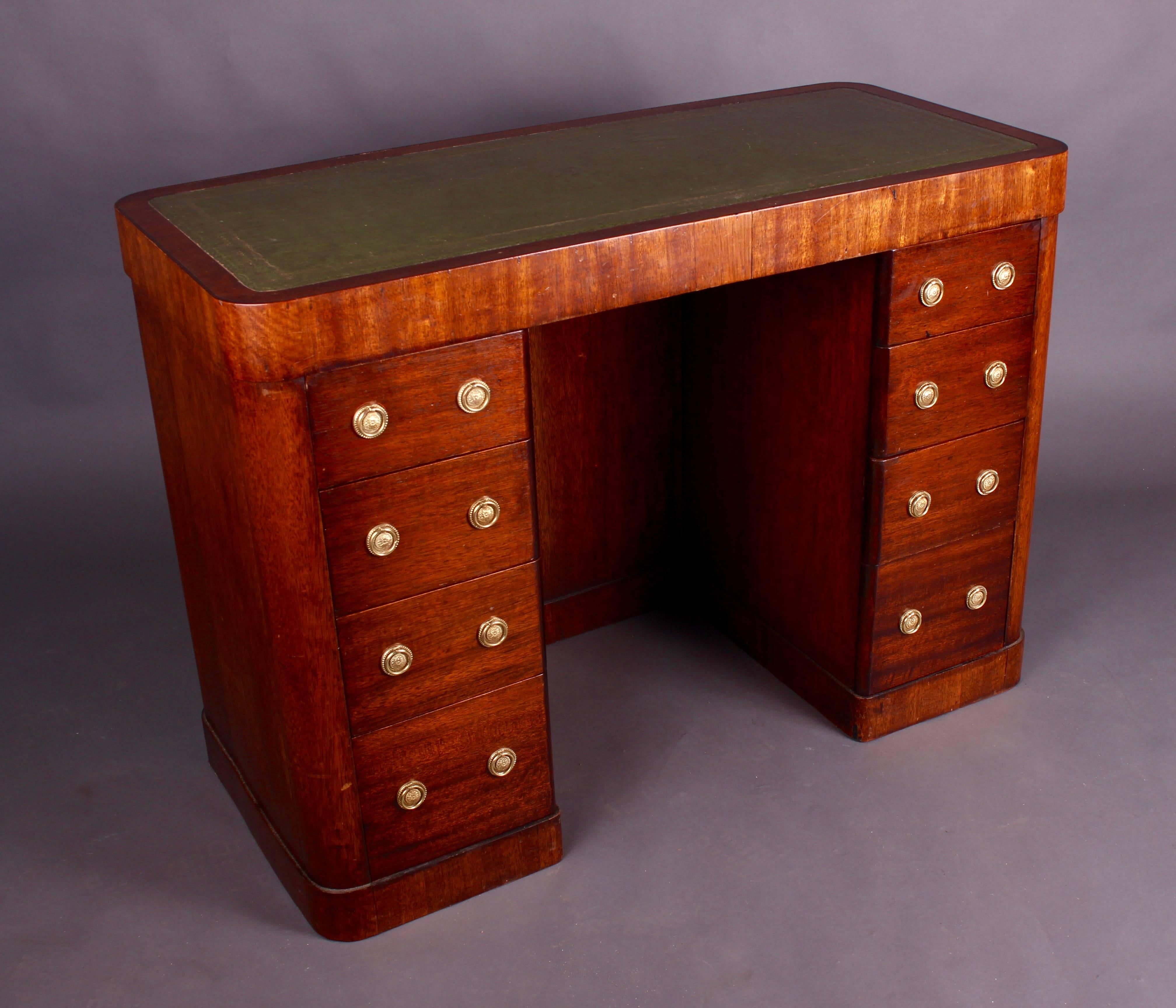 A lovely Art Deco writing desk crafted in oak with an inset tooled green leather inset skiver. Having nicely rounded corners to the desktop with an attractive leather inset. Two banks of four drawers below. The drawers having circular brass ring
