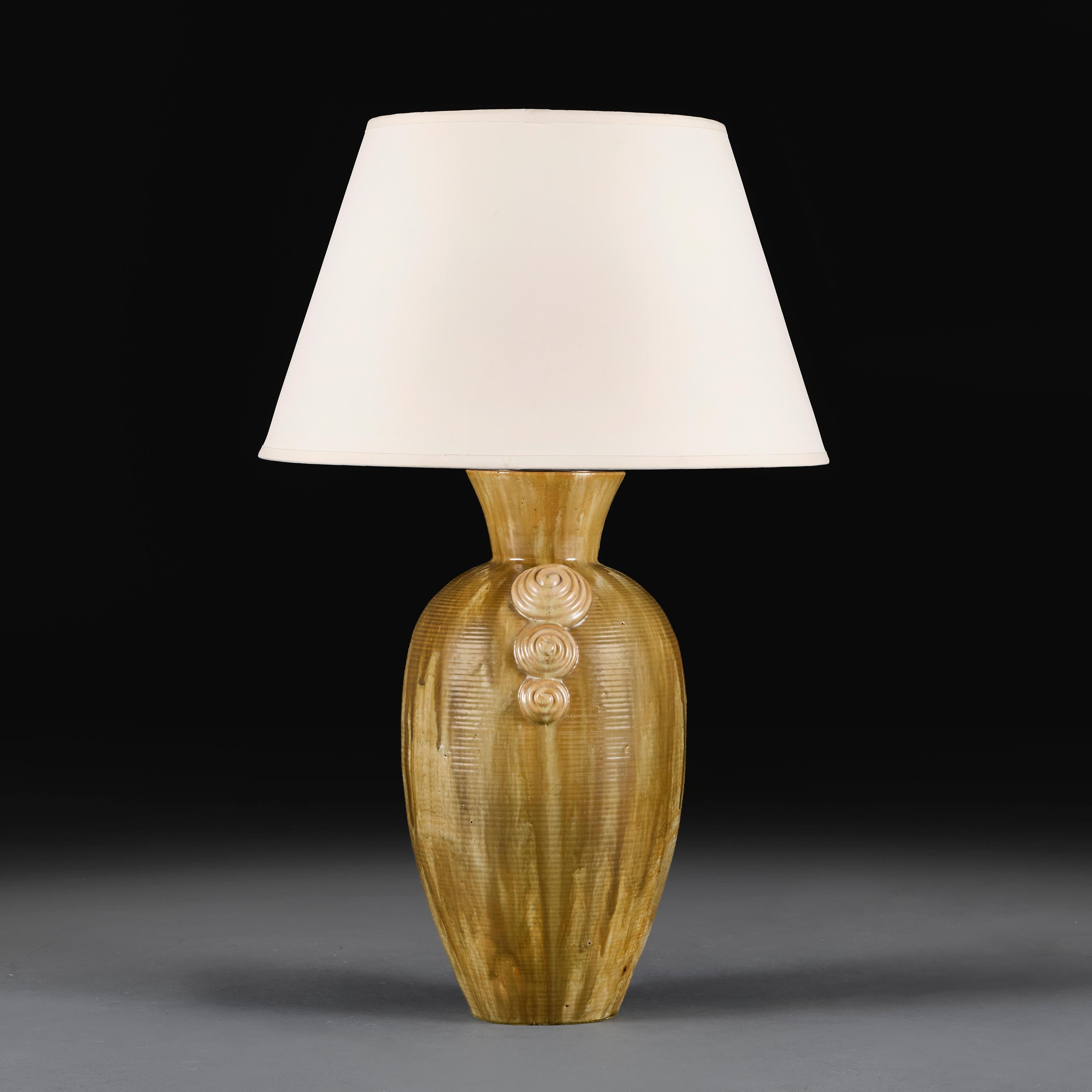 France, circa 1930.

An Art Deco period art pottery tapered vase with flared neck, decorated with a dripping olive brown glaze and applied graduating spirals to the shoulder and base, now mounted as a lamp.

Height 40.50 centimetres.
Height with