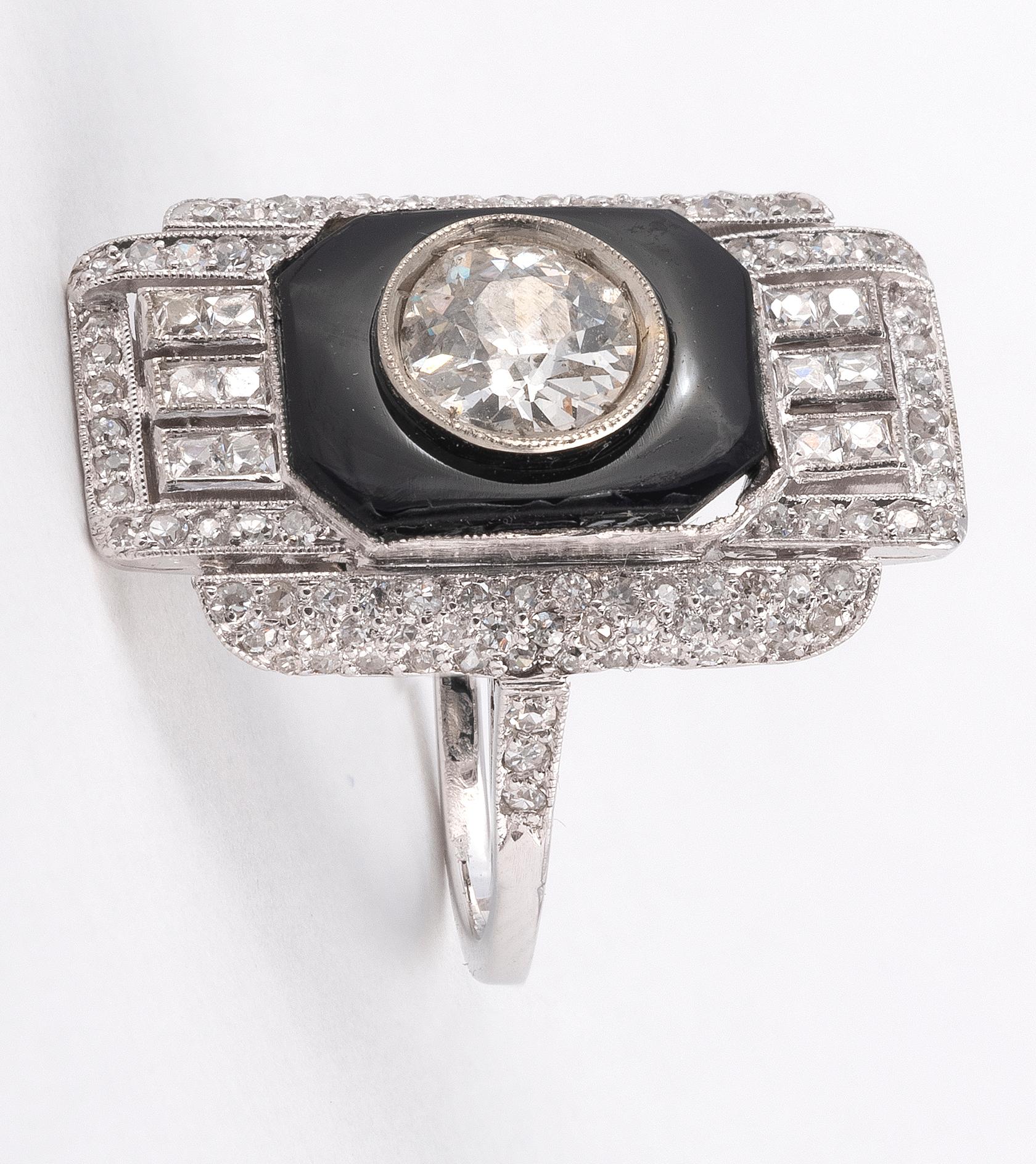 The rectangular plaque set at the centre with an old brilliant-cut diamond 1,7ct approximately, within a geometric frame of smaller similarly cut diamonds and onyx, finger size O