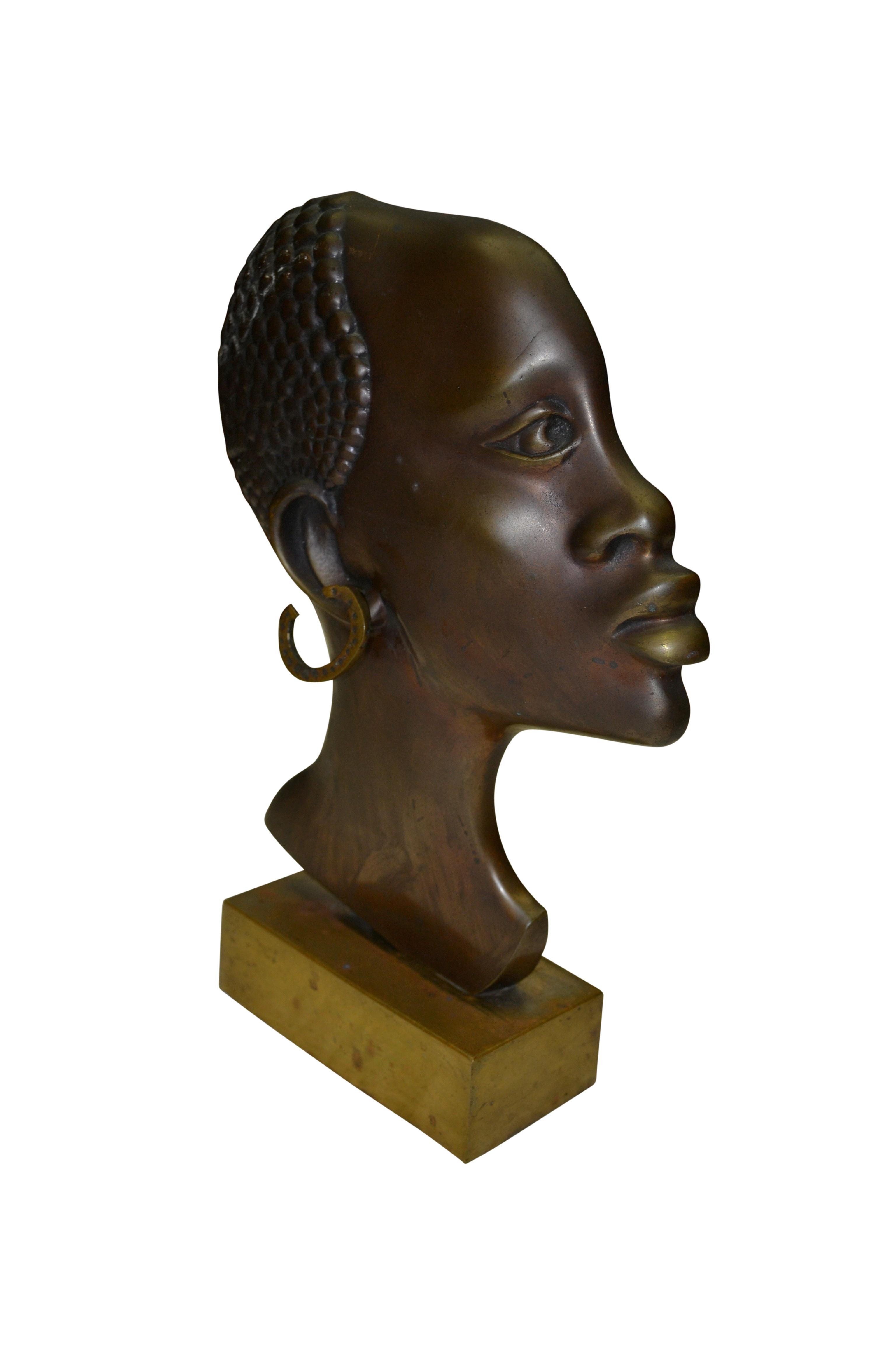 Busto de bronce bien fundido de perfil de una mujer africana sobre una base rectangular de latón. No está firmado y no tiene marcas. El origen podría ser la propia África o Francia Periodo Art Déco.