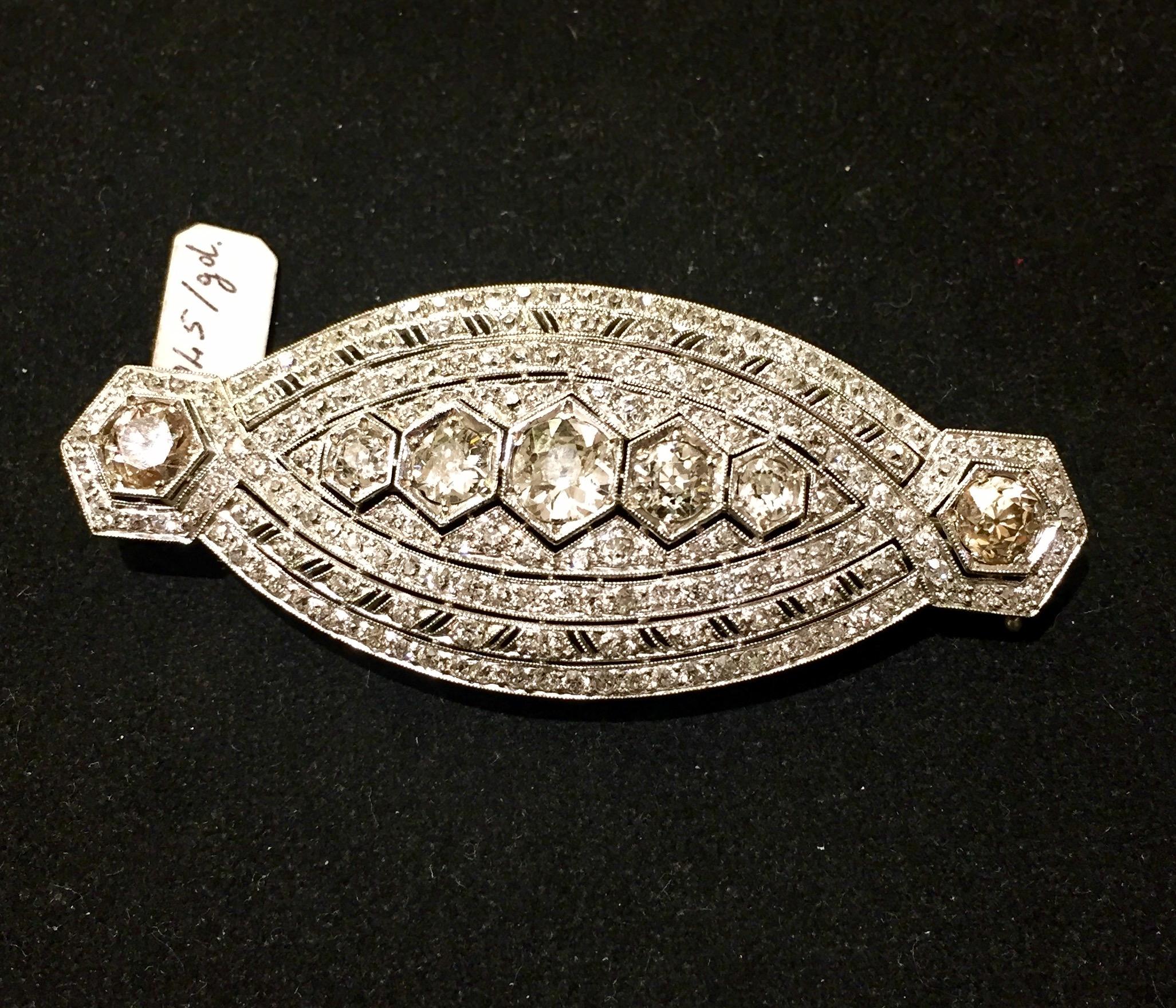 An Art Deco Platinum and Diamond Pendant/Brooch, consisting of a pierced filigree design and millegrain details, containing 7 old European cut diamond weighing approximately 4,5 carats, the other old European cut diamonds weighing approximately 2.50