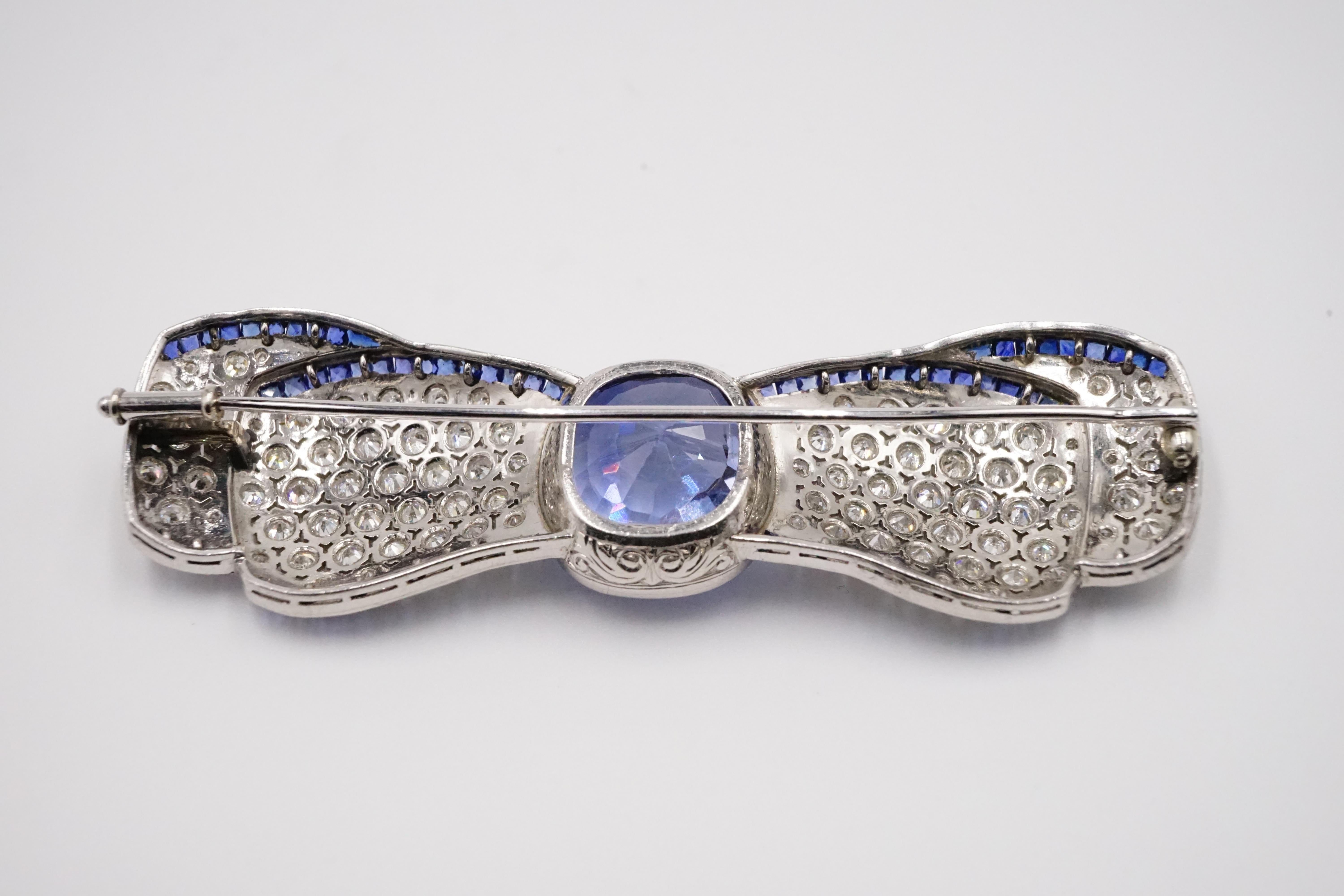 An amazing art deco bow brooch for all occasions.

At the centre is a large rectangular cushion natural Sri Lanka sapphire measures W:14mm H:16mm D:9.4mm the sapphire is surrounded by 92 perfectly matched diamonds then 84 equally brilliant sapphires