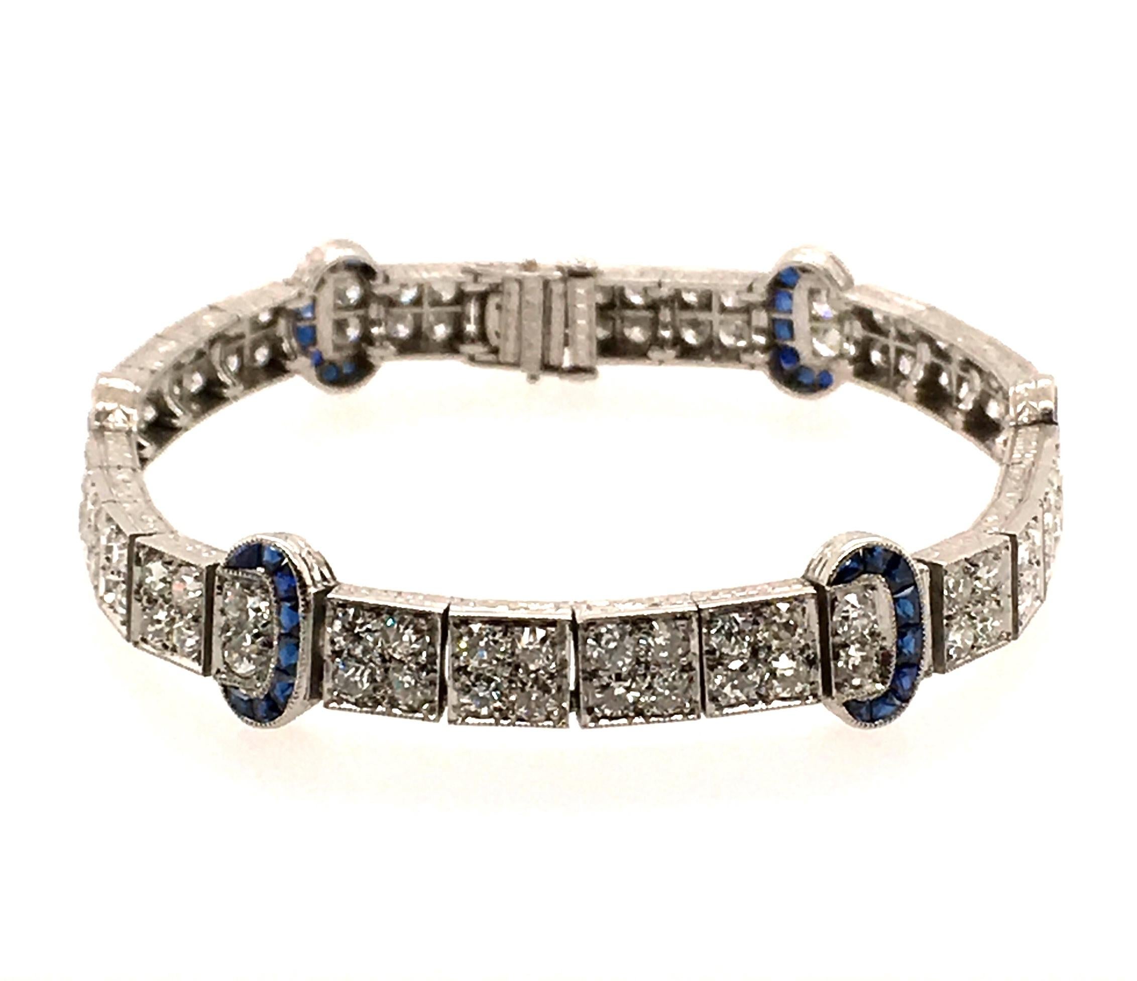 An art deco platinum, diamond and sapphire bracelet. Circa 1925. Designed as a pave set diamond flexible band, enhanced by French cut sapphire buckle motifs. One hundred and four  old European cut diamonds weigh approximately 4.70 carats. Length is
