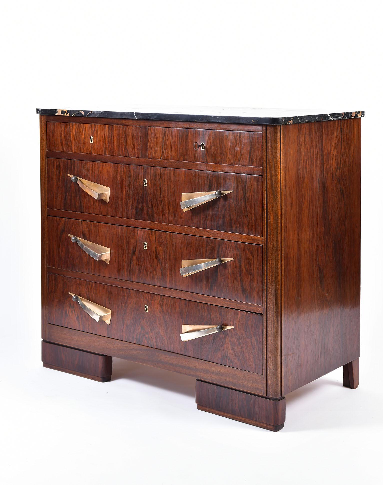 An Art Deco rosewood and Portoro marble-top chest of drawers, the five drawers with brass and nickel plate brass handles and brass key holes, with a key in working order, on rounded rectangular feet.
France, circa 1930.