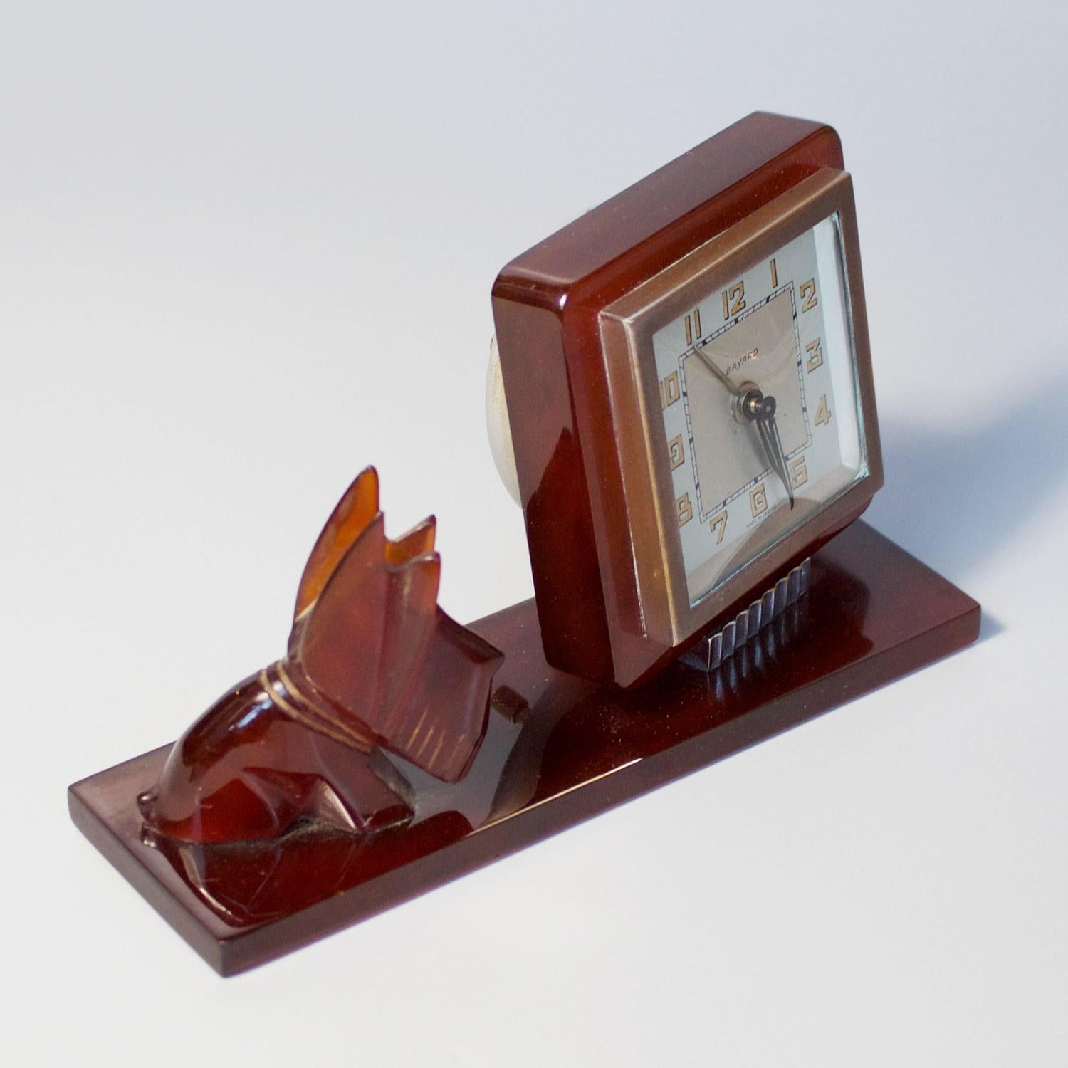 An Art Deco alarm desk clock by Bayard. Amber bakelite with a Scottie dog sitting beside the Bakelite framed clock face. Original 8-day movement. Chrome detail. 

Dimensions: H 10cm W 16cm D 5cm

Origin: French

Date: circa 1930

Item