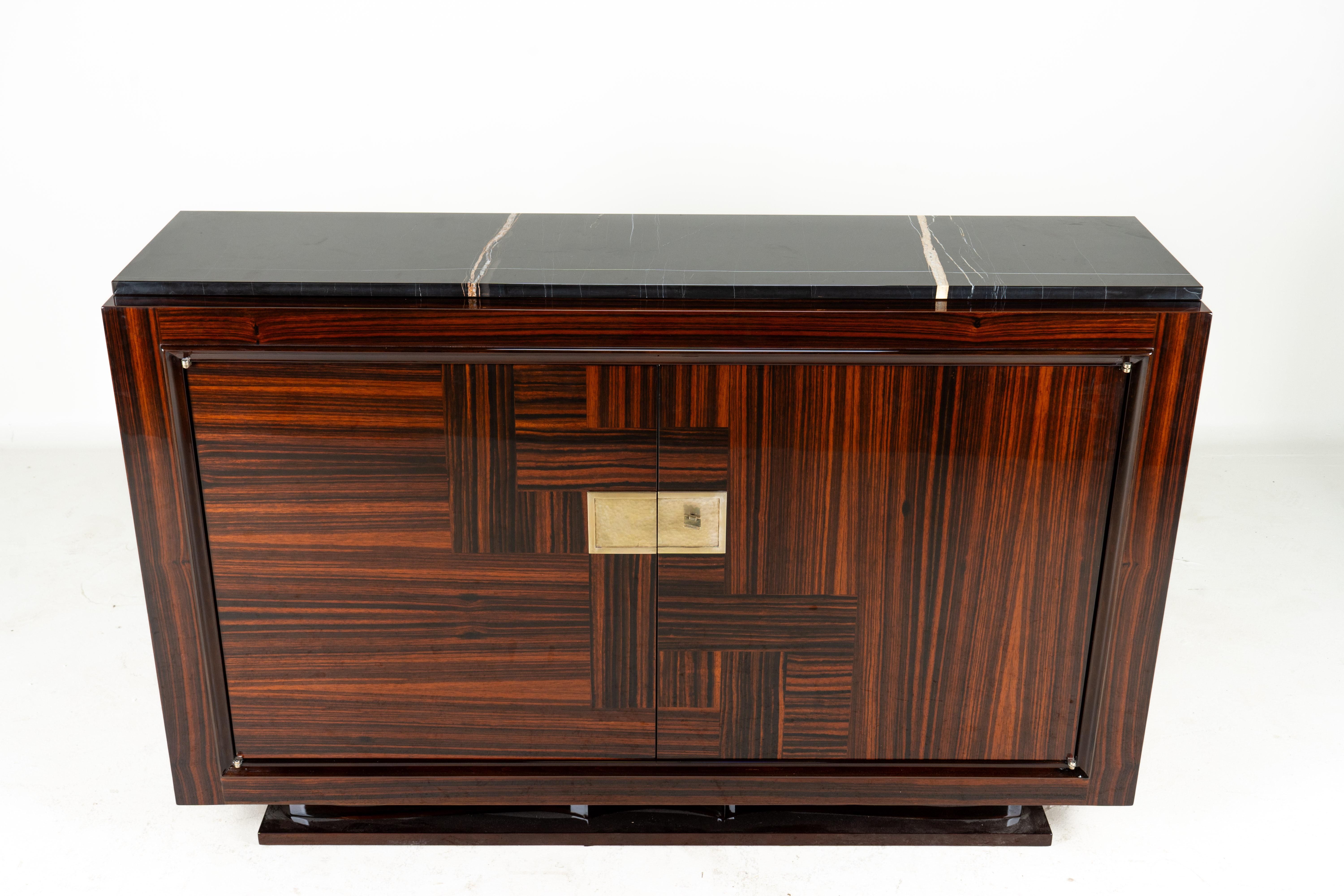 This is an exceptionally simple and elegant vintage Art Deco sideboard dating to the 1940's. The macassar wood is strikingly laid out in a perpendicular parquetry pattern and polished to a high gloss. The central lock plate is nickel, having a