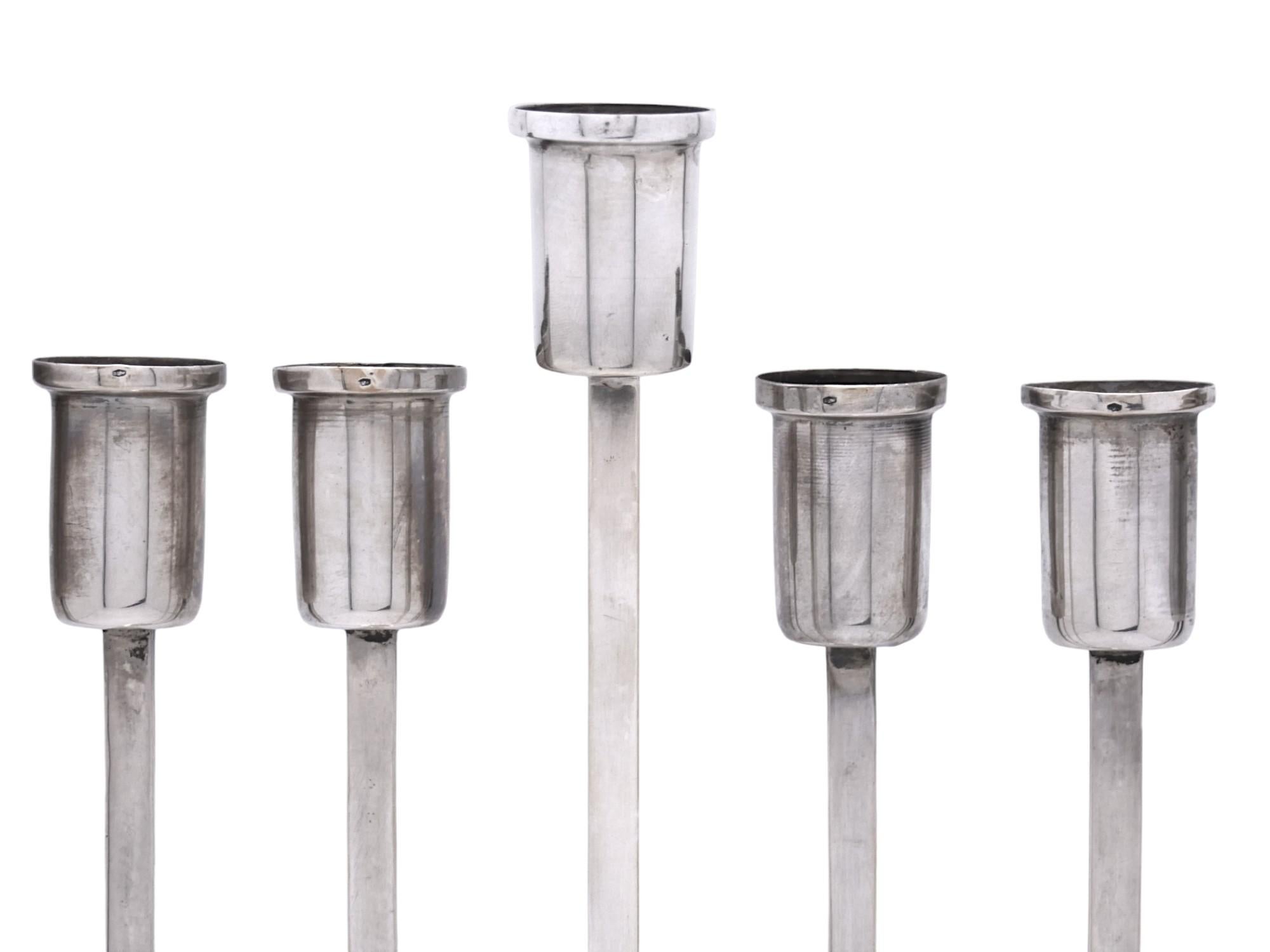 Splendida Menorah di Hanukkah in argento martellato austriaco realizzata nello stile Art Deco di quel periodo di transizione dello stile.

La menorah è incastonata in una forma esagonale piatta montata su una base a cupola martellata con uno stelo