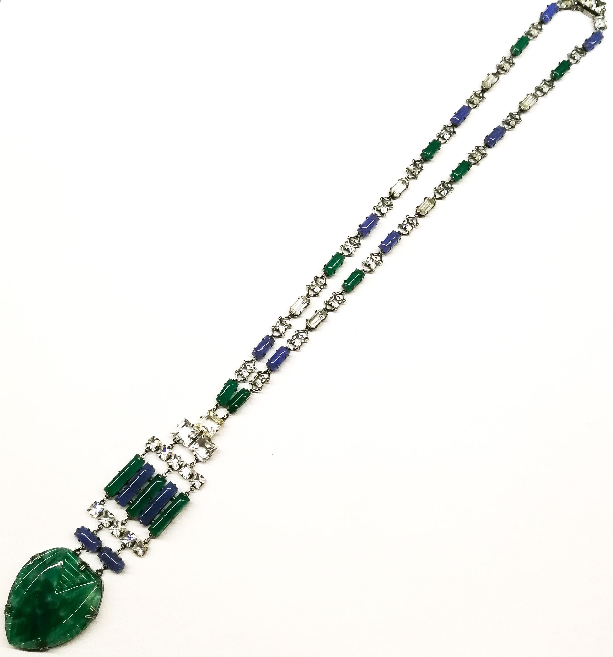 An outstanding Art Deco pendant necklace in highly characteristic colour and design.
It is composed of blue and green chalcedony glass rounded baguettes throughout, highlighted with clear cut paste rectangular and square faceted stones. The striking