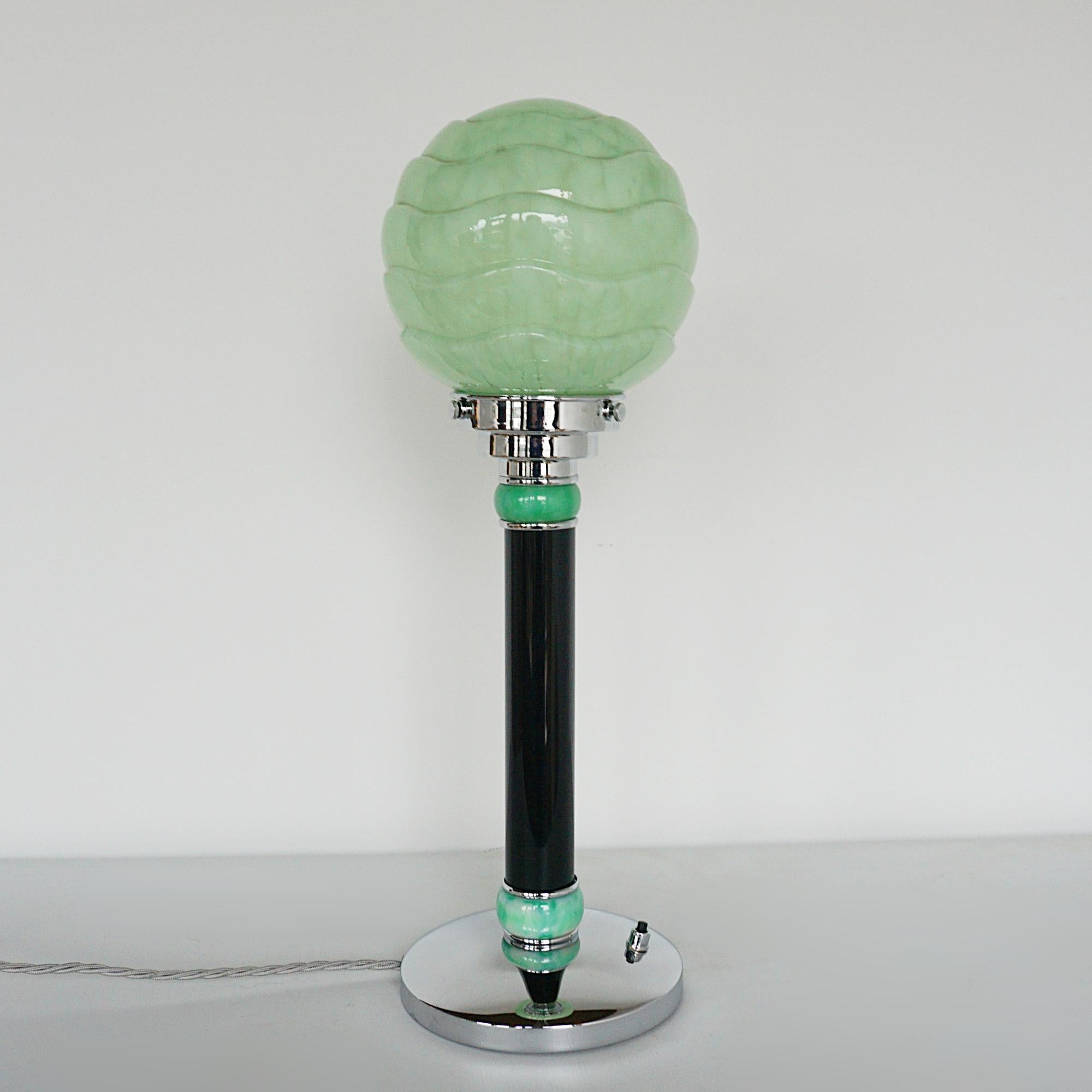 An Art Deco style table lamp. Black bakelite stem with mottled green caps, chromed circular base and a mottled green glass shade.

Dimensions: H 49cm, W 16cm

Origin: English

Item No: J349

All of our lighting is fully refurbished, re-wired, and