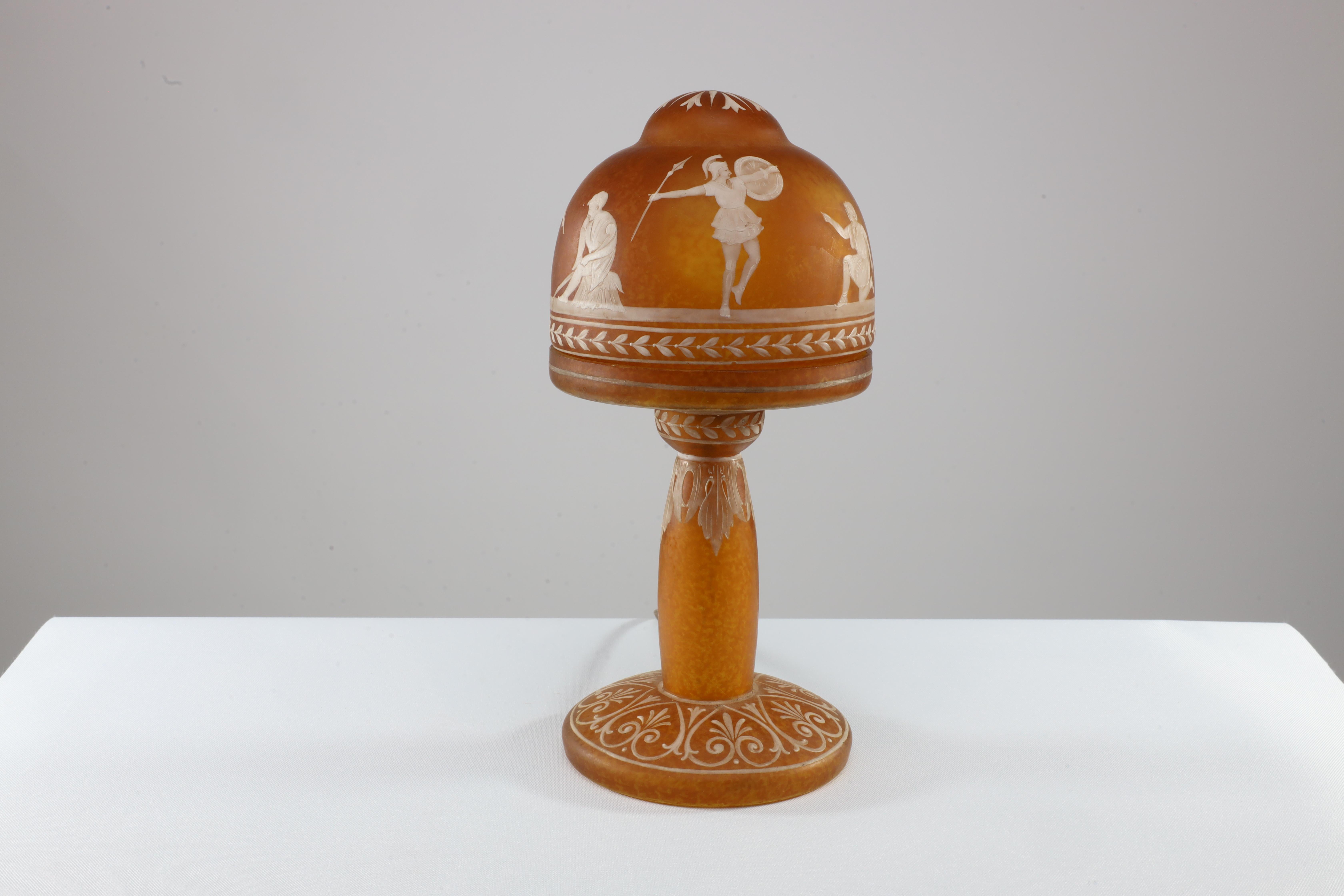 An Art Deco style motteled orange hand painted Cameo Glass style table lamp with lotus leaves to the top shade and Greek Gods, warriors, and a Boy and Lady standing with leaf decoration to the stem and Greek key decoration to the base.