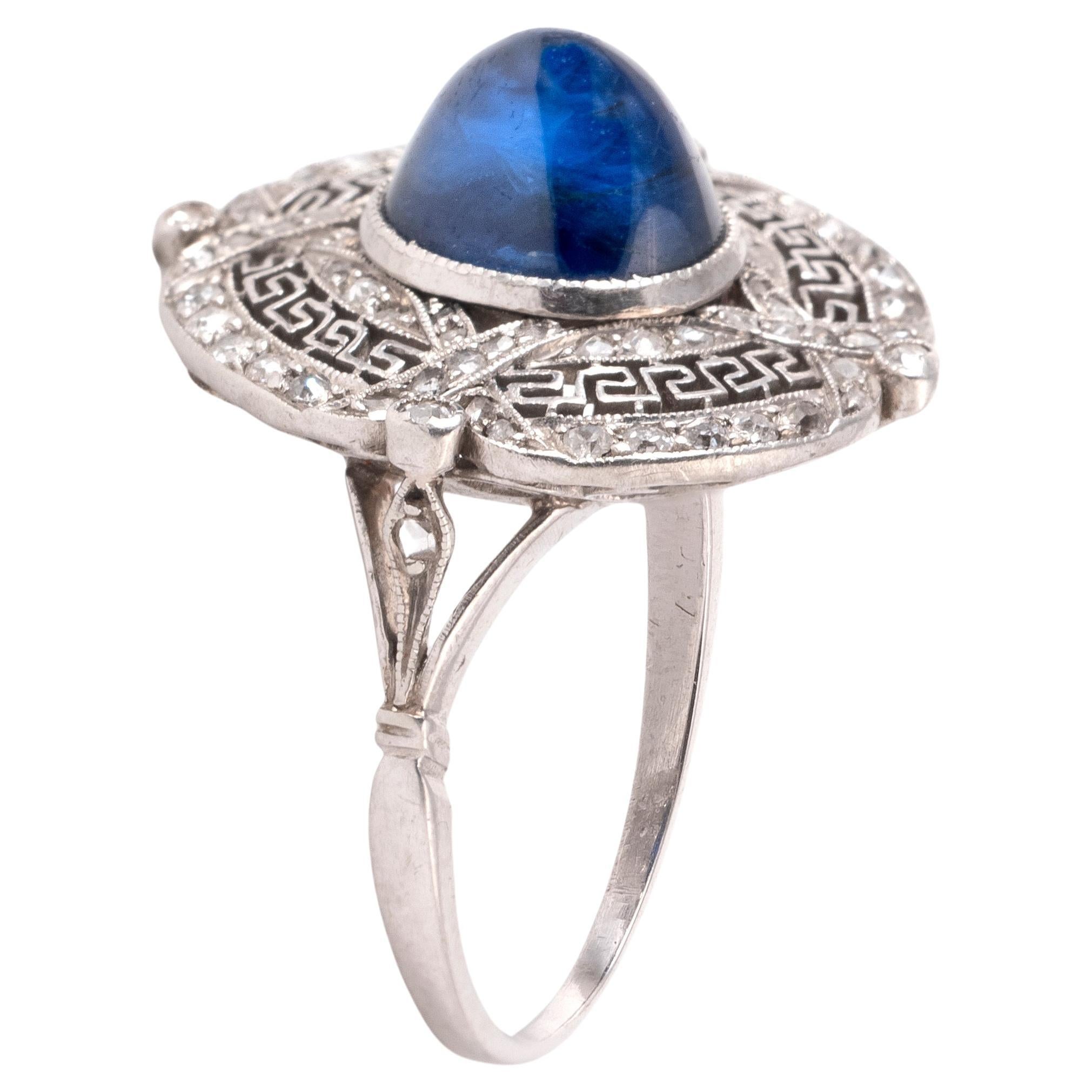The sapphire oval sugarloaf cabochon approximately 3ct within an round-shaped plaque geometric set with old brilliant-cut diamonds, the shoulders partially-set with similarly-cut diamonds, mounted in platinum, diamonds approx. 1.10cts total.
Ring