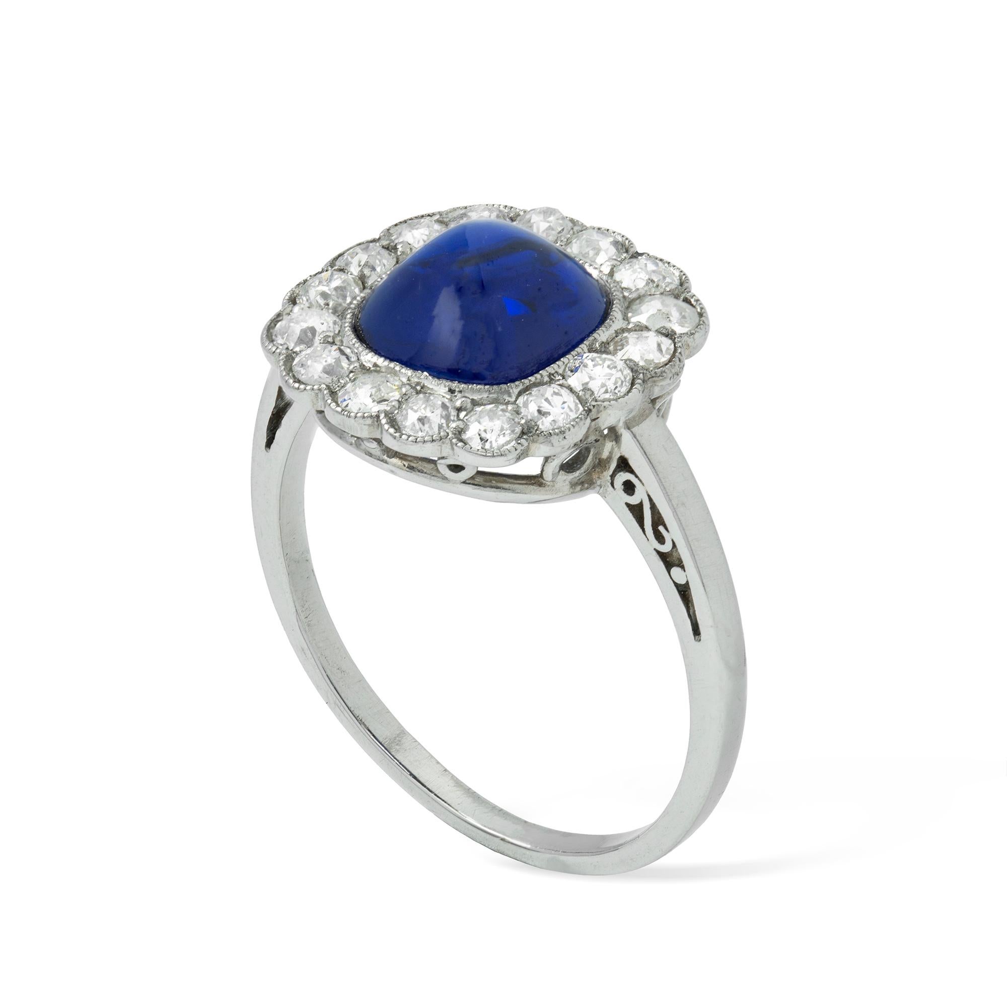 An early 20th century sugarloaf sapphire and diamond ring, the cushion-cut sapphire, accompanied by SSEF Report stating that is of Burmese origin with no indications of heating, weighing approximately 2.7 carats, millegrain-set within a cluster of
