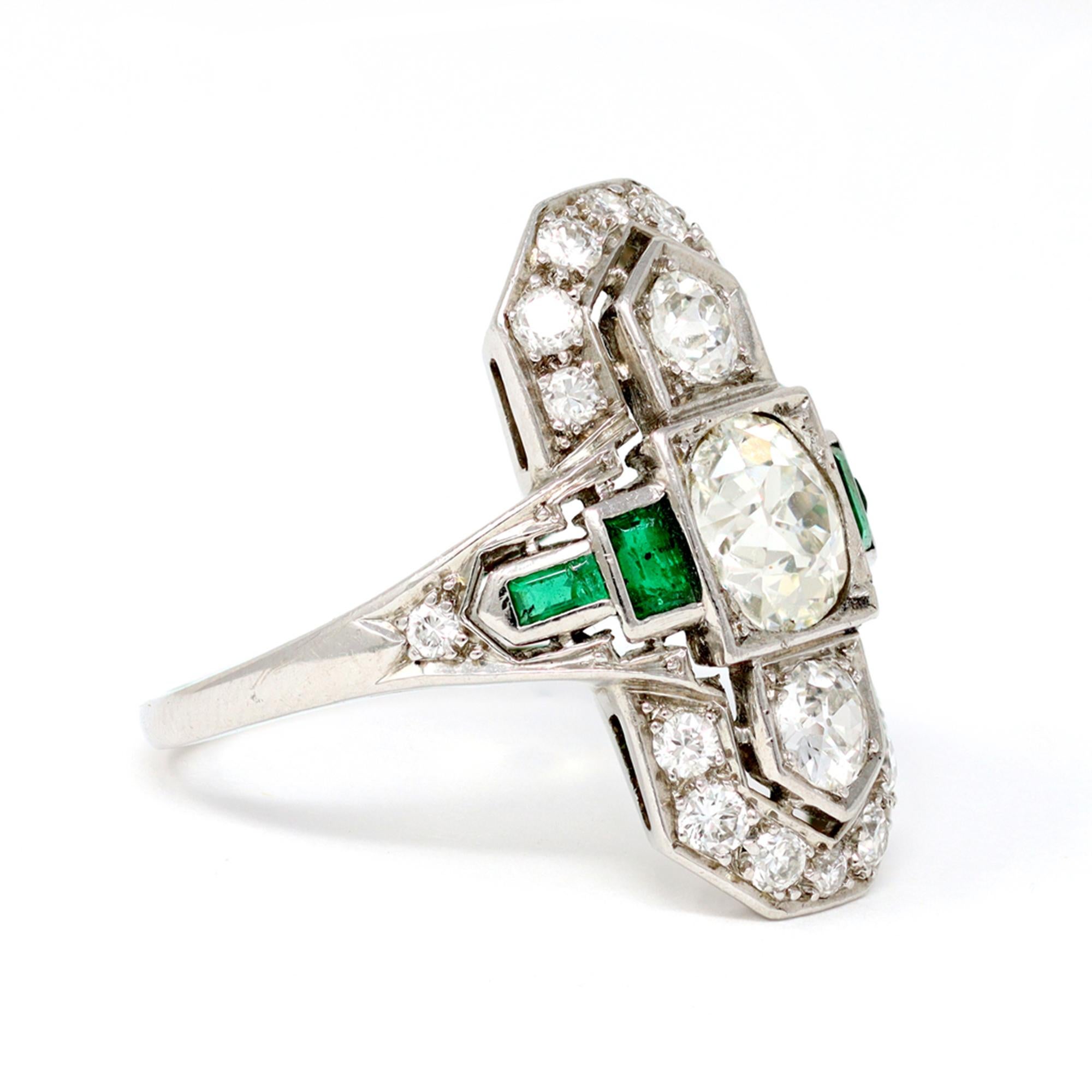 The Art Deco three stone diamond ring is set in platinum with diamonds and emeralds. Designed as an elongated geometric plaque circa 1930 and set with 3 old European-cut diamonds weighing approximately 1.50 carats, the ring is framed with small