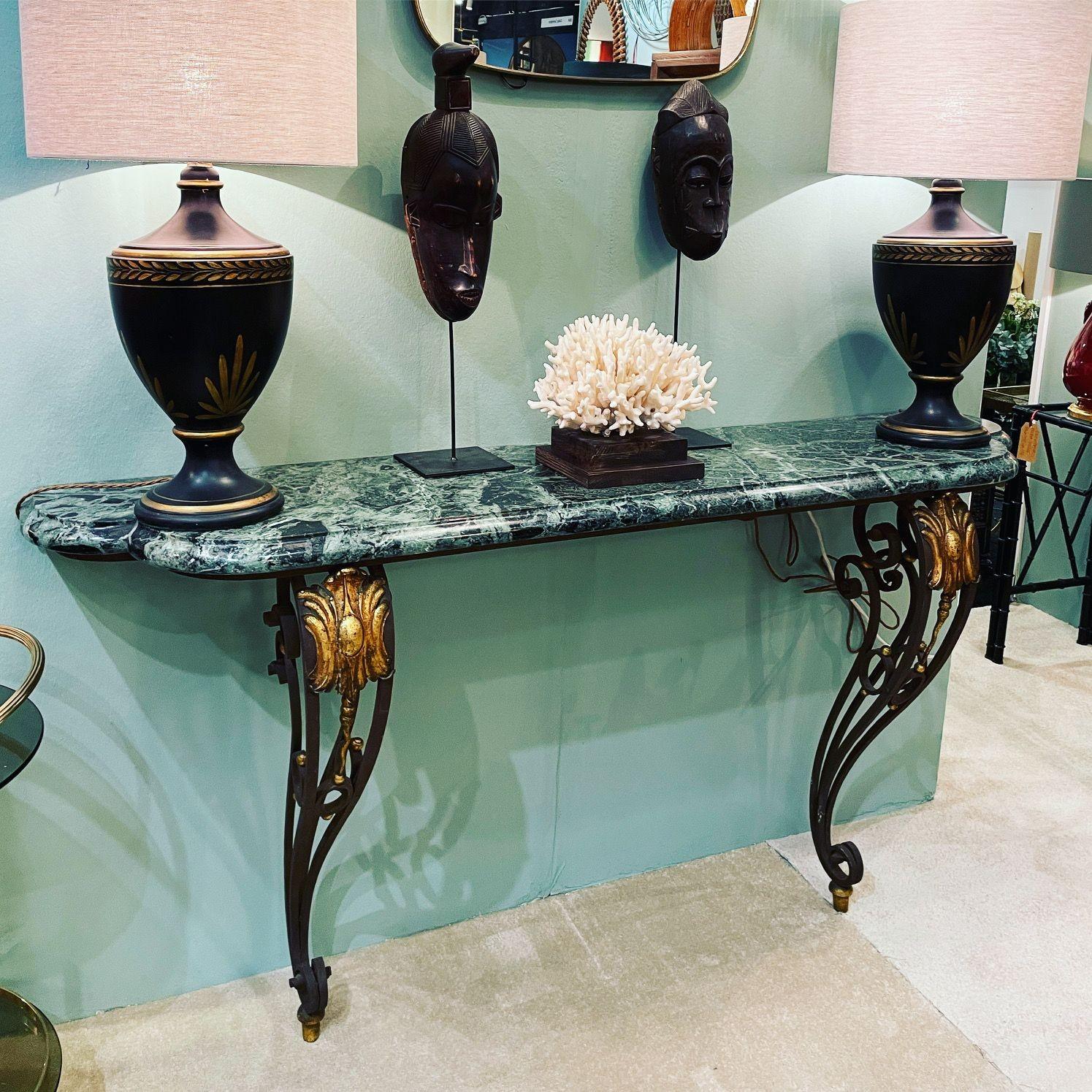 An Art Deco wrought iron console table in the style of Gilbert Poillerat with solid curved green marble top, mounted on wrought iron curved and detailed wall mounted base, with gilded details.
