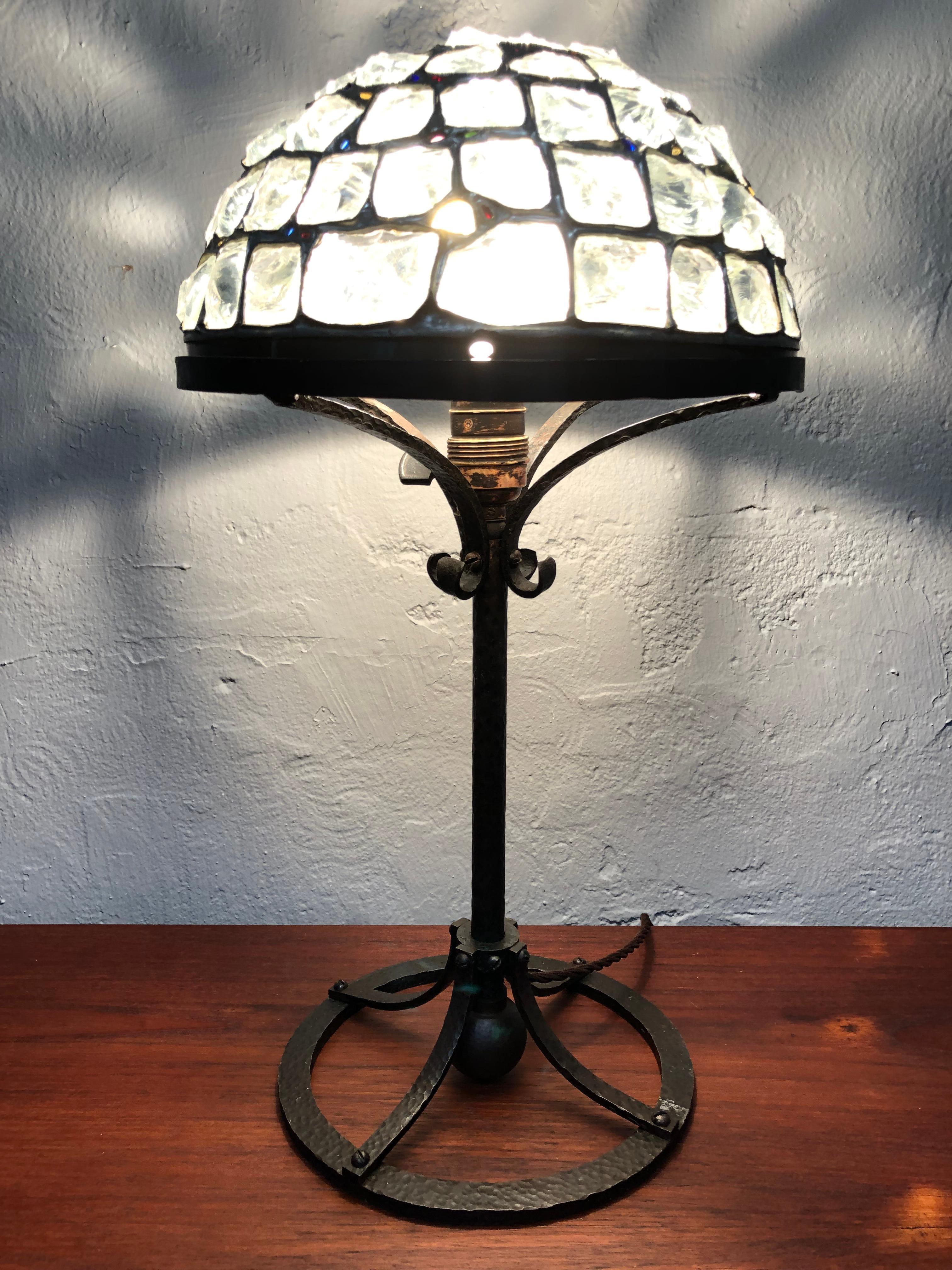 An Art Deco wrought iron table lamp with a stunning leaded glass shade which looks fantastic lit up in the dark. 
A piece of artwork in its own right. 
In great original condition and still maintaining its original E27 brass and porcelain lamp