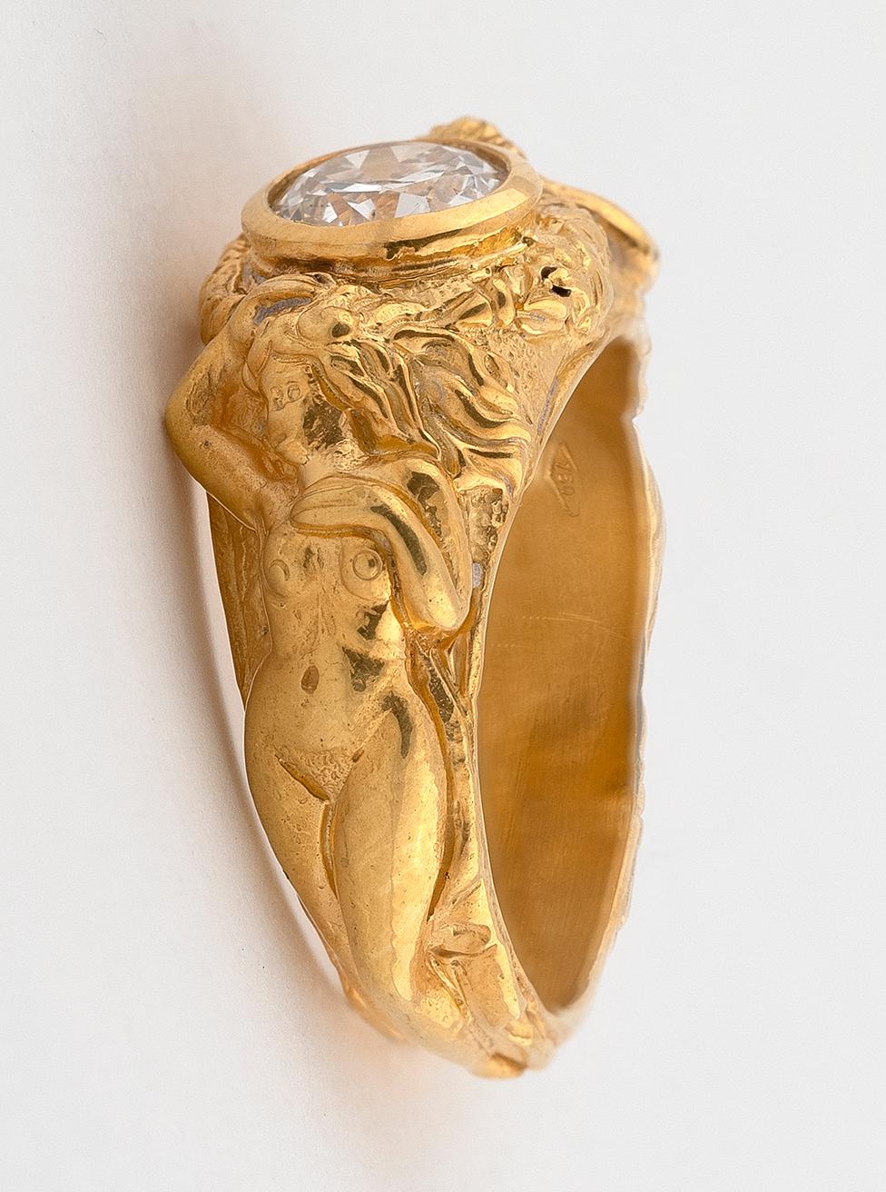  the collet-mounted diamond to a hoop modelled as faun and the virgin emerging from foliage, diamond approx. 
1.20ct.
Size: 8
