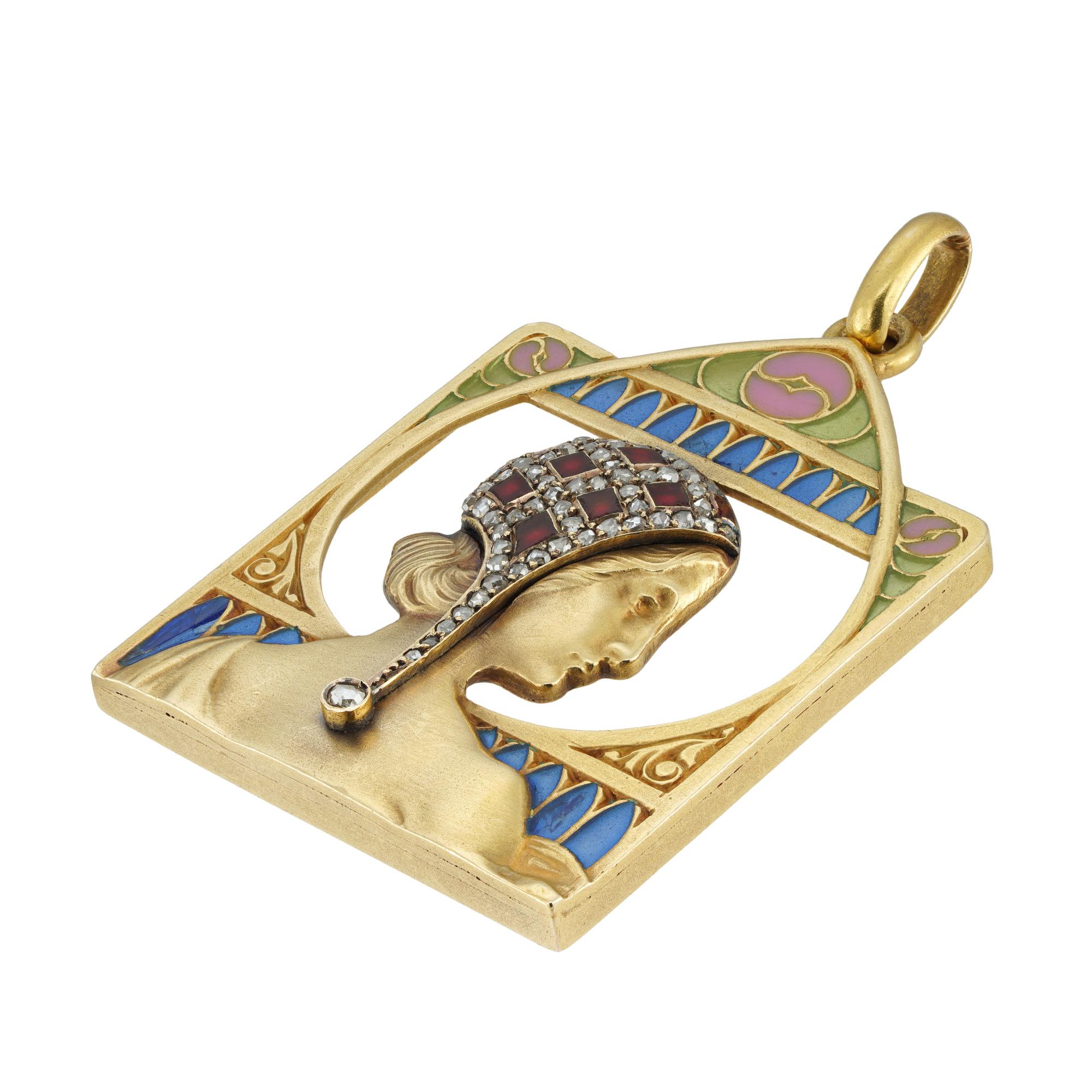 Pendentif Art Nouveau en émail, diamants et or par Masriera, représentant une dame de profil portant une coiffe émaillée rouge agrémentée de décorations serties de diamants taillés en rose, dans un cadre géométrique ajouré avec des décorations en