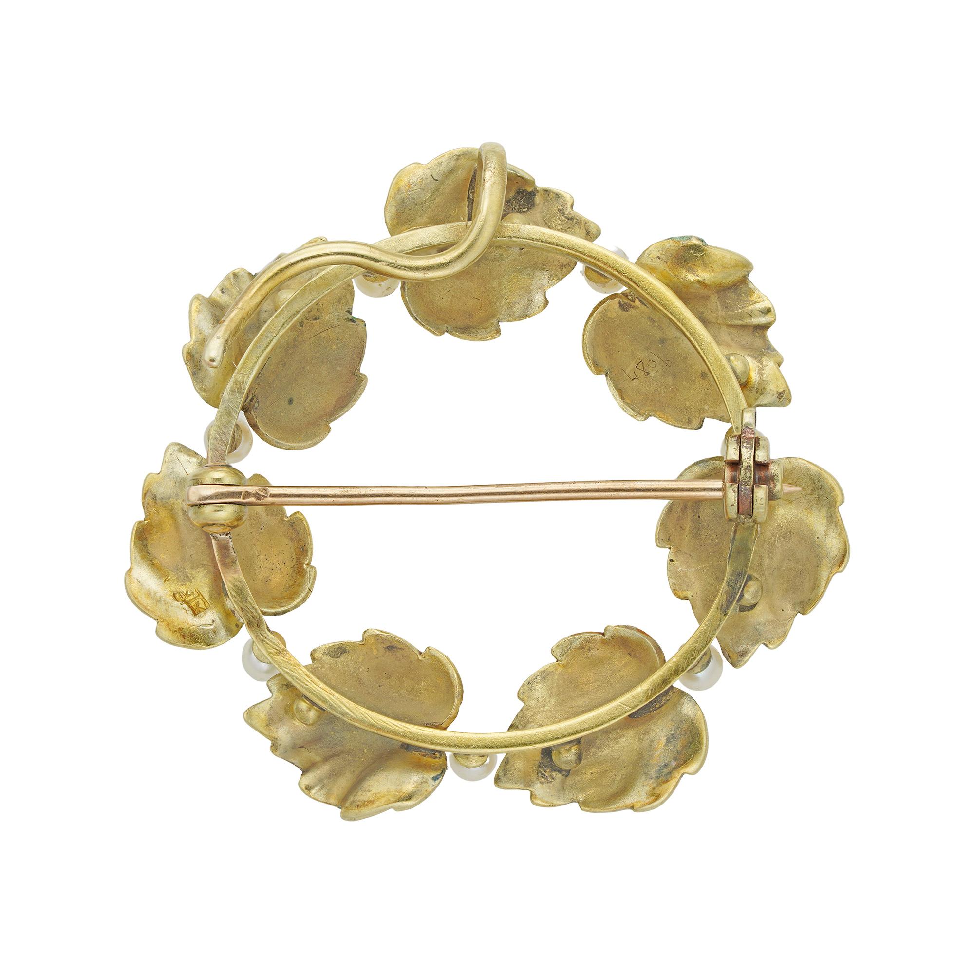 An Art Nouveau enamel wreath brooch, consisting of seven enamelled mulberry tree leaves, with seed pearls set in-between, all mounted in yellow gold, tested as 18ct gold with 14ct gold pin, circa 1900, probably American, measuring approximately
