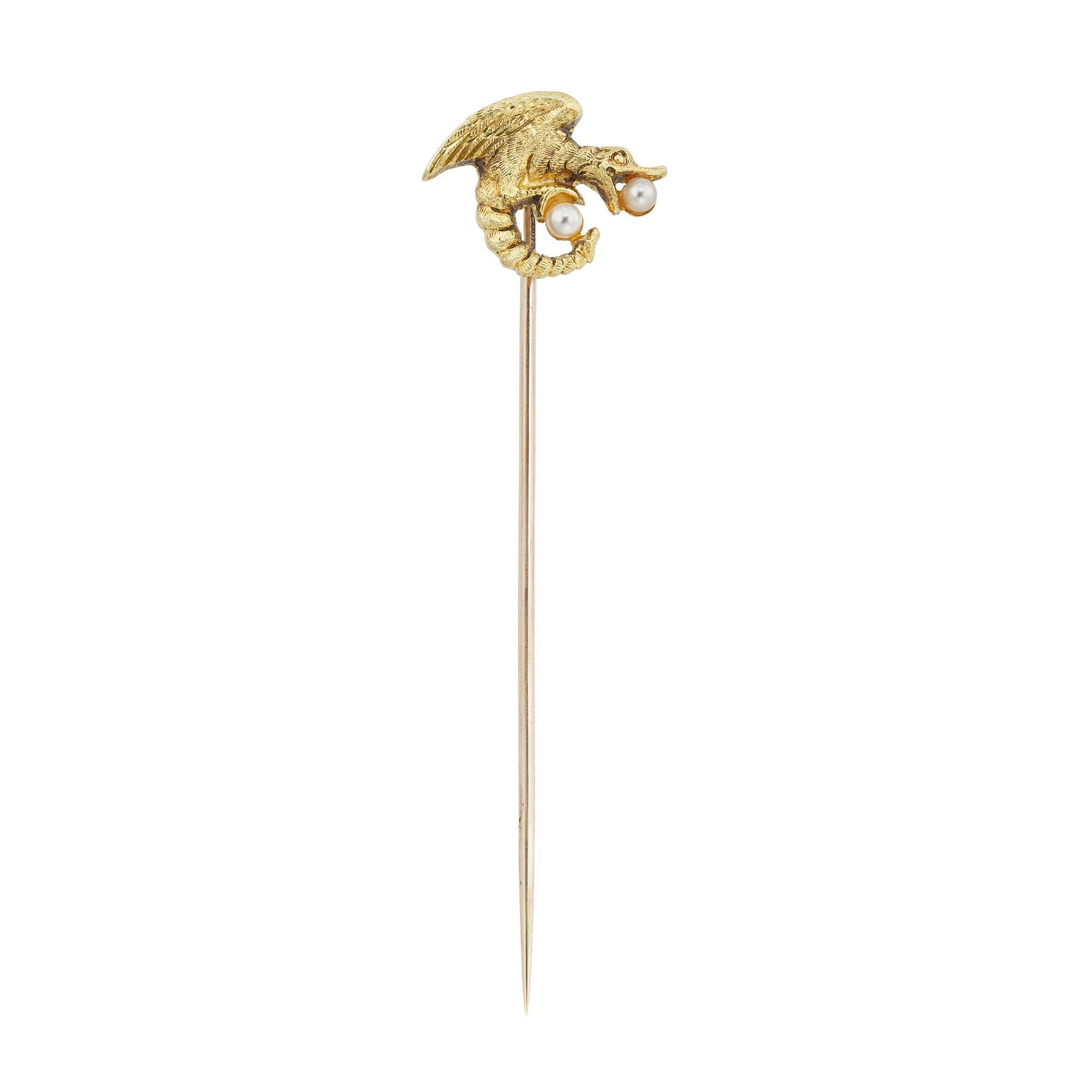 An Art Nouveau gold stick pin, depicting a dragon holding one round seed pearl in its jaws and another seed pearl in its claws, circa 1890, the jewelled part measuring approximately 1.1x1.45cm, the pin measuring 5.5cm long, gross weight 1.2