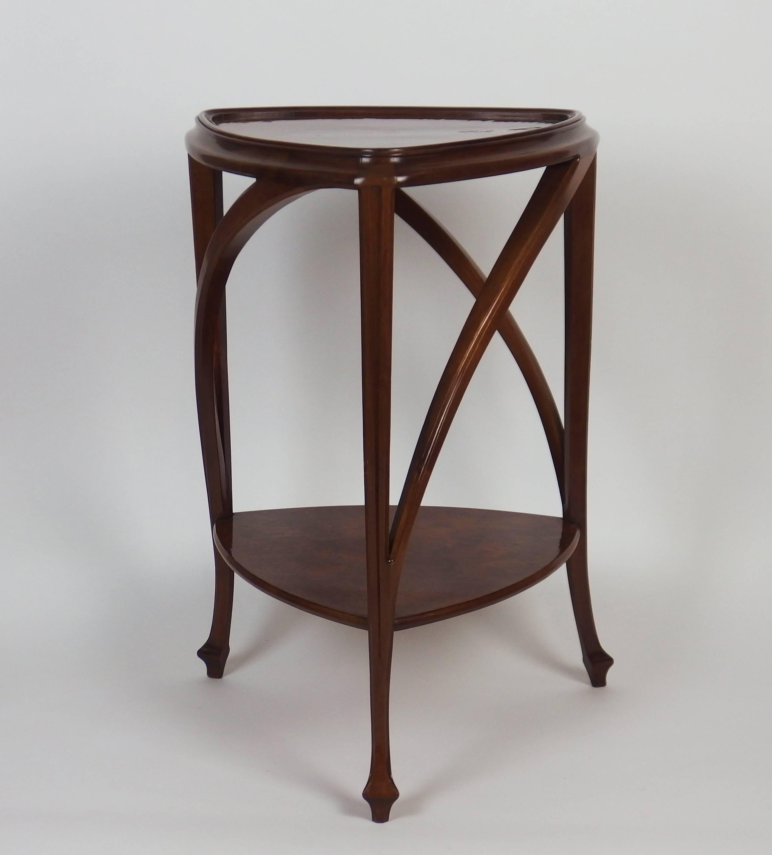 A triangular burr walnut top on mahogany moulded buttressed supports and legs joined by a similar platform stretcher. Designed by Louis Majorelle, circa 1910.