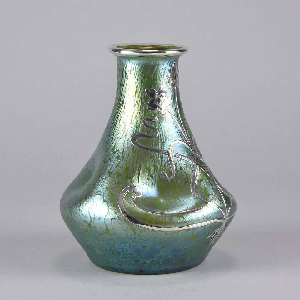 Excellent early 20th century Art Nouveau green glass dimpled vase of bulbous form with fine petrol blue iridescent surface and further applied with a silver Art Nouveau organic floral decoration to the body and neck of the vase. A fine example of an
