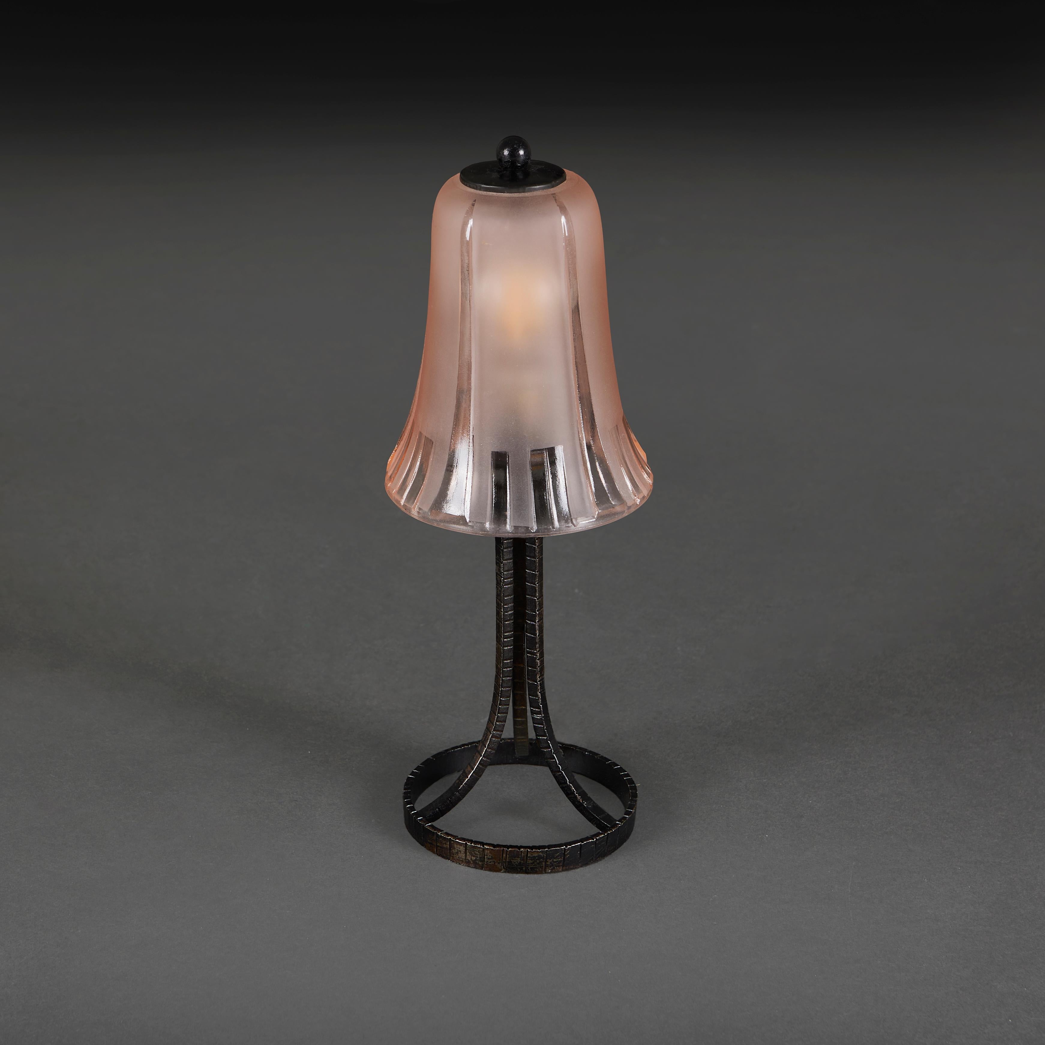 Pequeña lámpara art nouveau de hierro forjado con pantalla de cristal rosa.