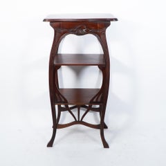 An Art Nouveau mahogany three tier plant stand with shallow floral carving