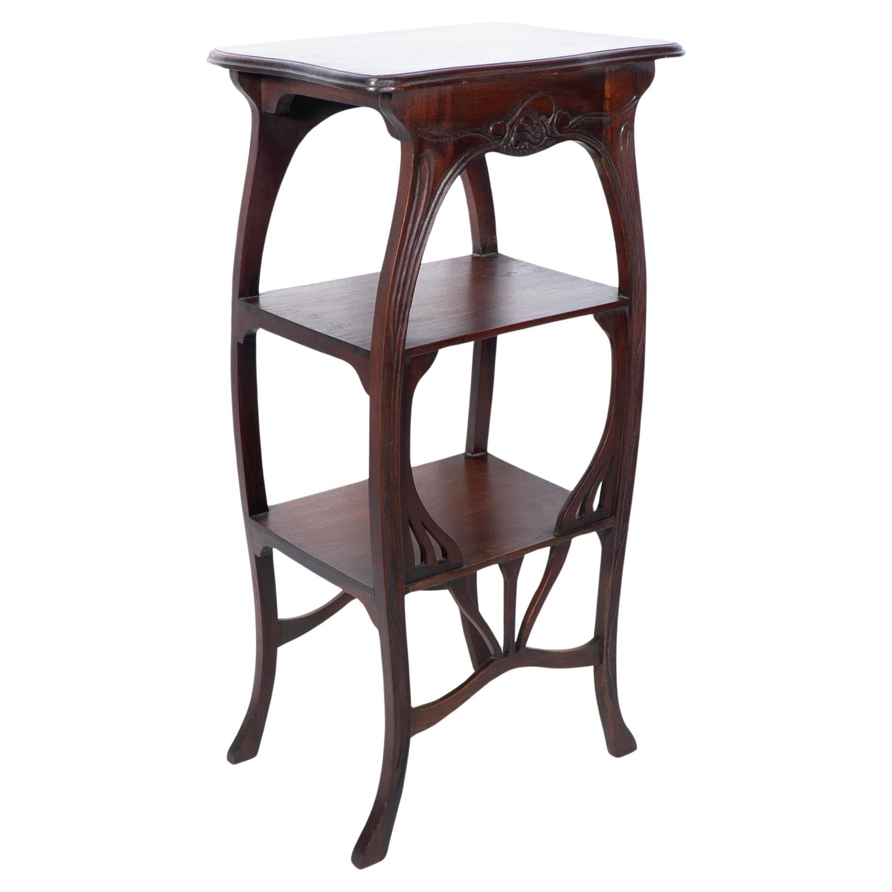 An Art Nouveau mahogany three tier plant stand with shallow floral carving